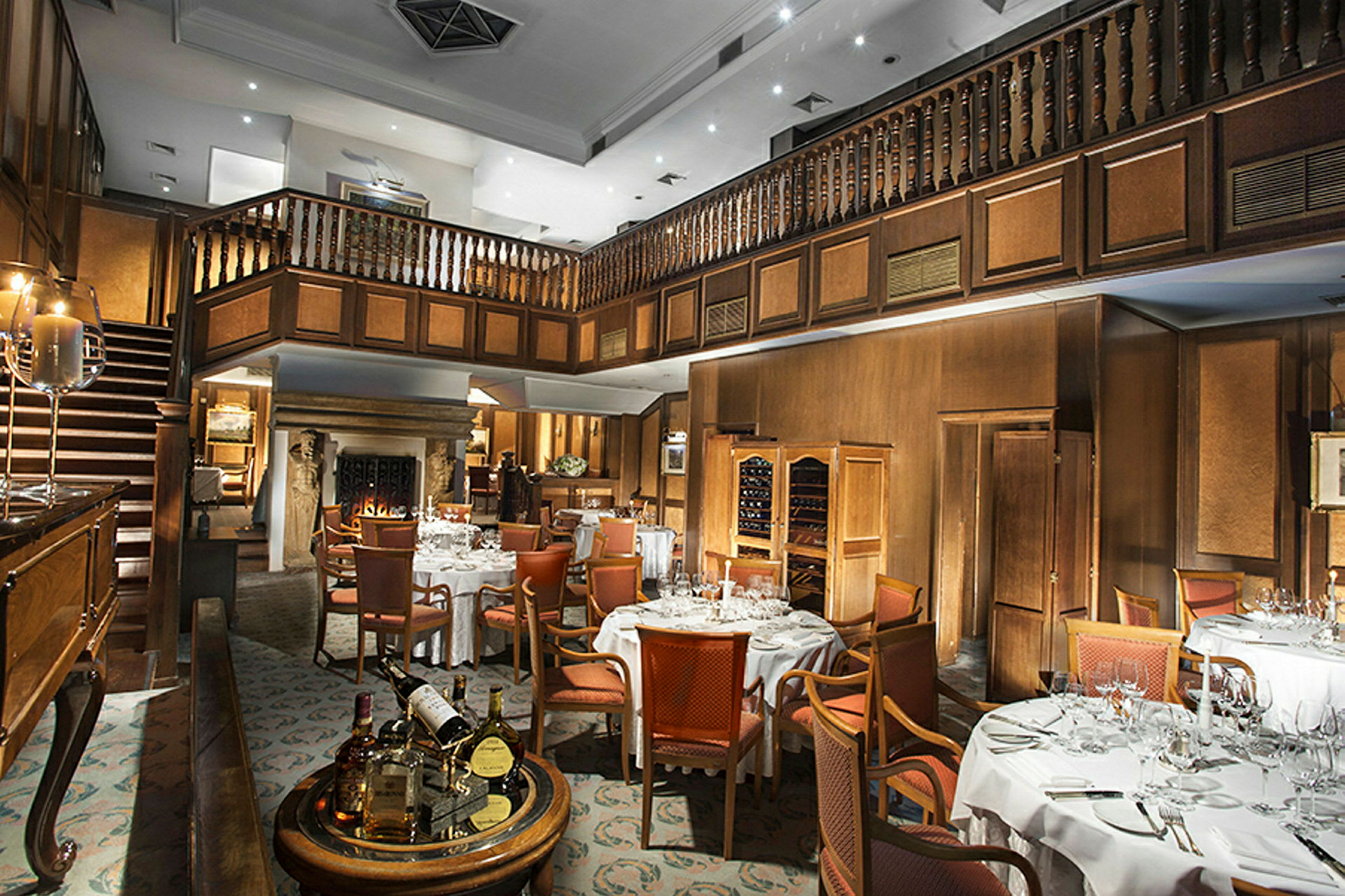 En stilfull restaurang med dukade bord, klassiska trädetaljer och en öppen spis. (AI-genererad text)