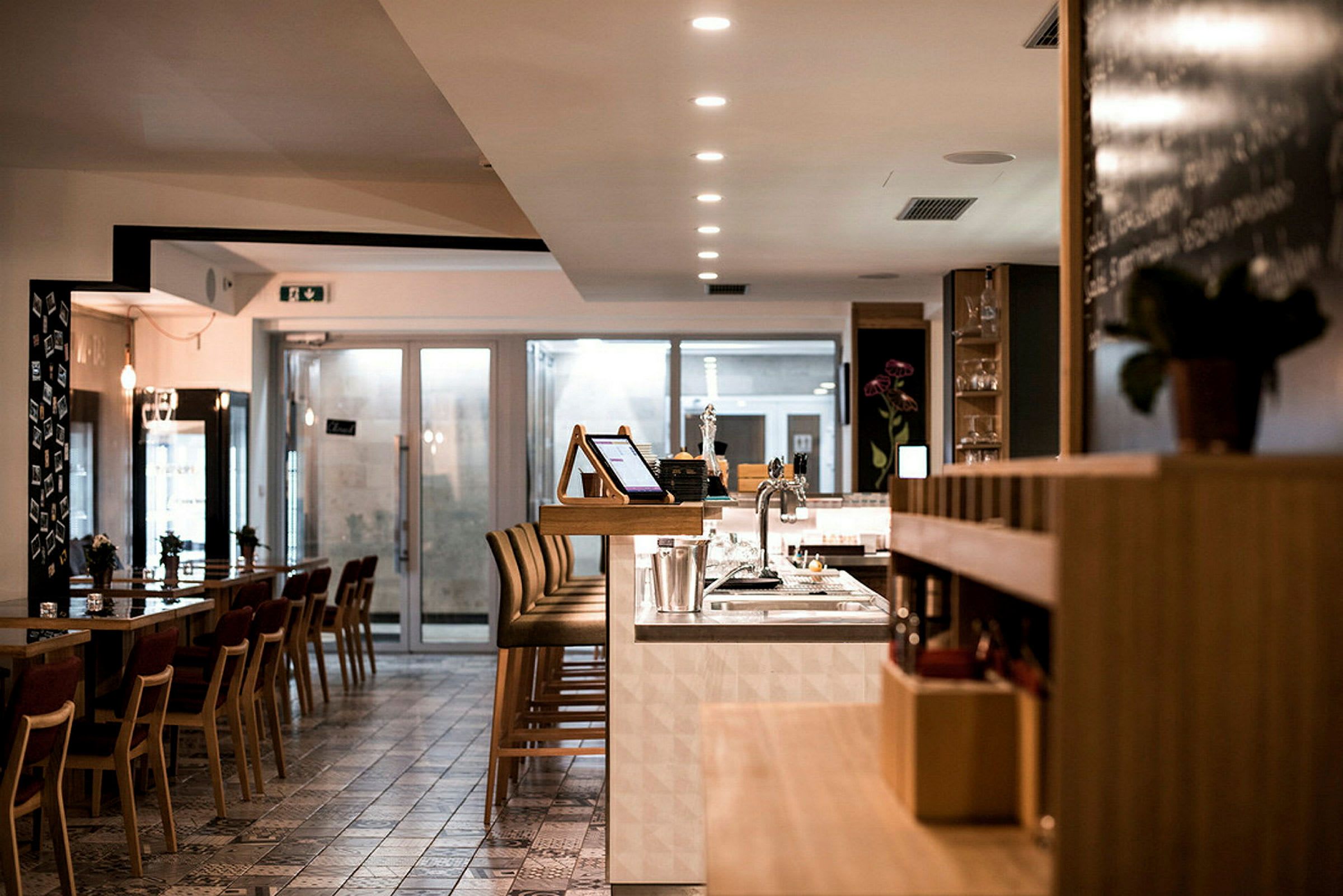 Interiör av en modern restaurang med bord, stolar och en bardisk. (AI-genererad text)