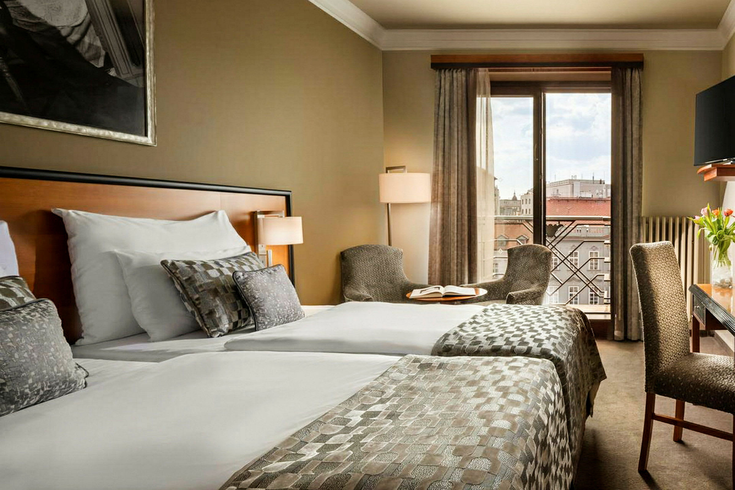 Hotellrum med två bäddar, sittplatser och utsikt över staden. (AI-genererad text)