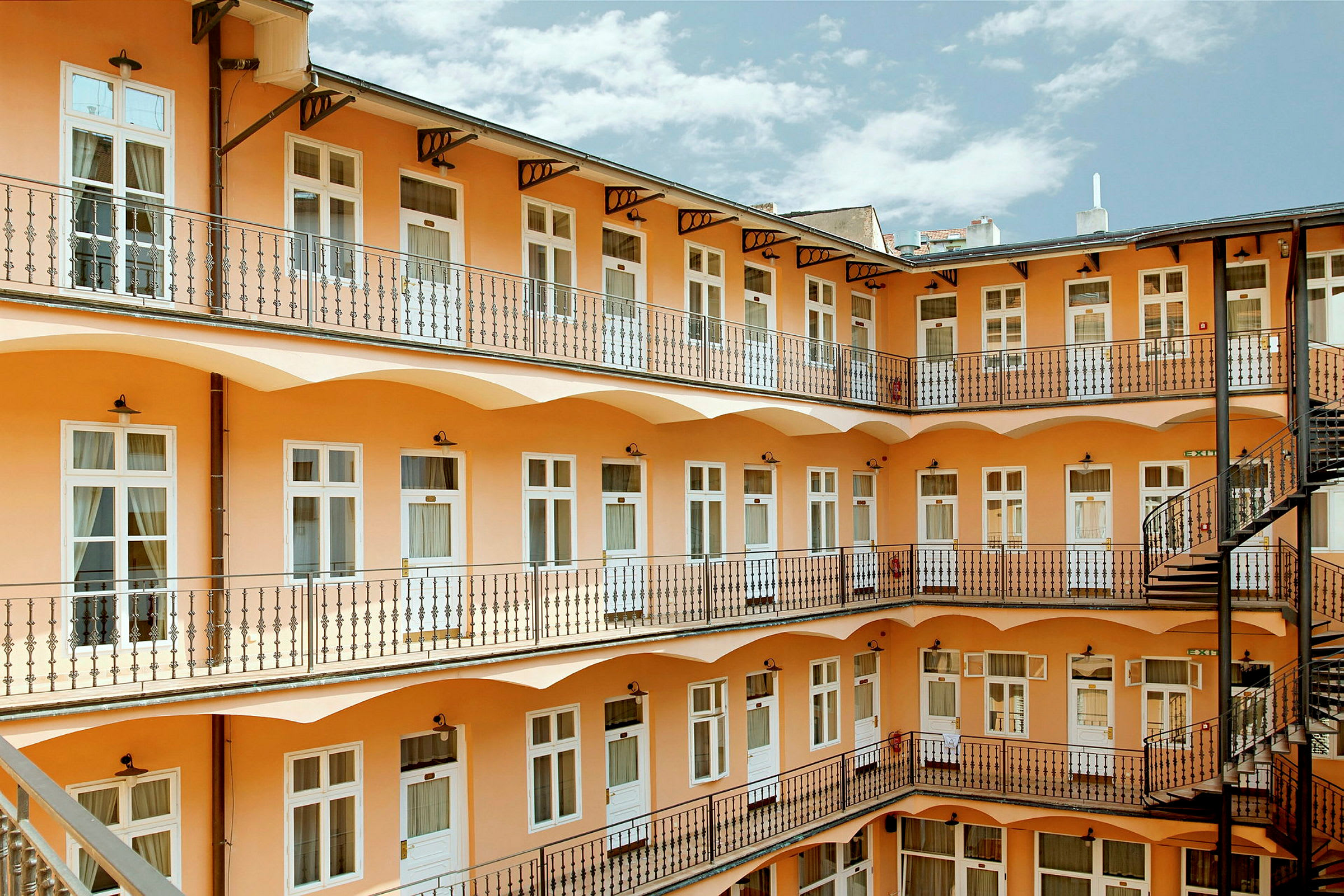 Innergård med flera våningsplan dekorerat med fönster och räcken. (AI-genererad text)