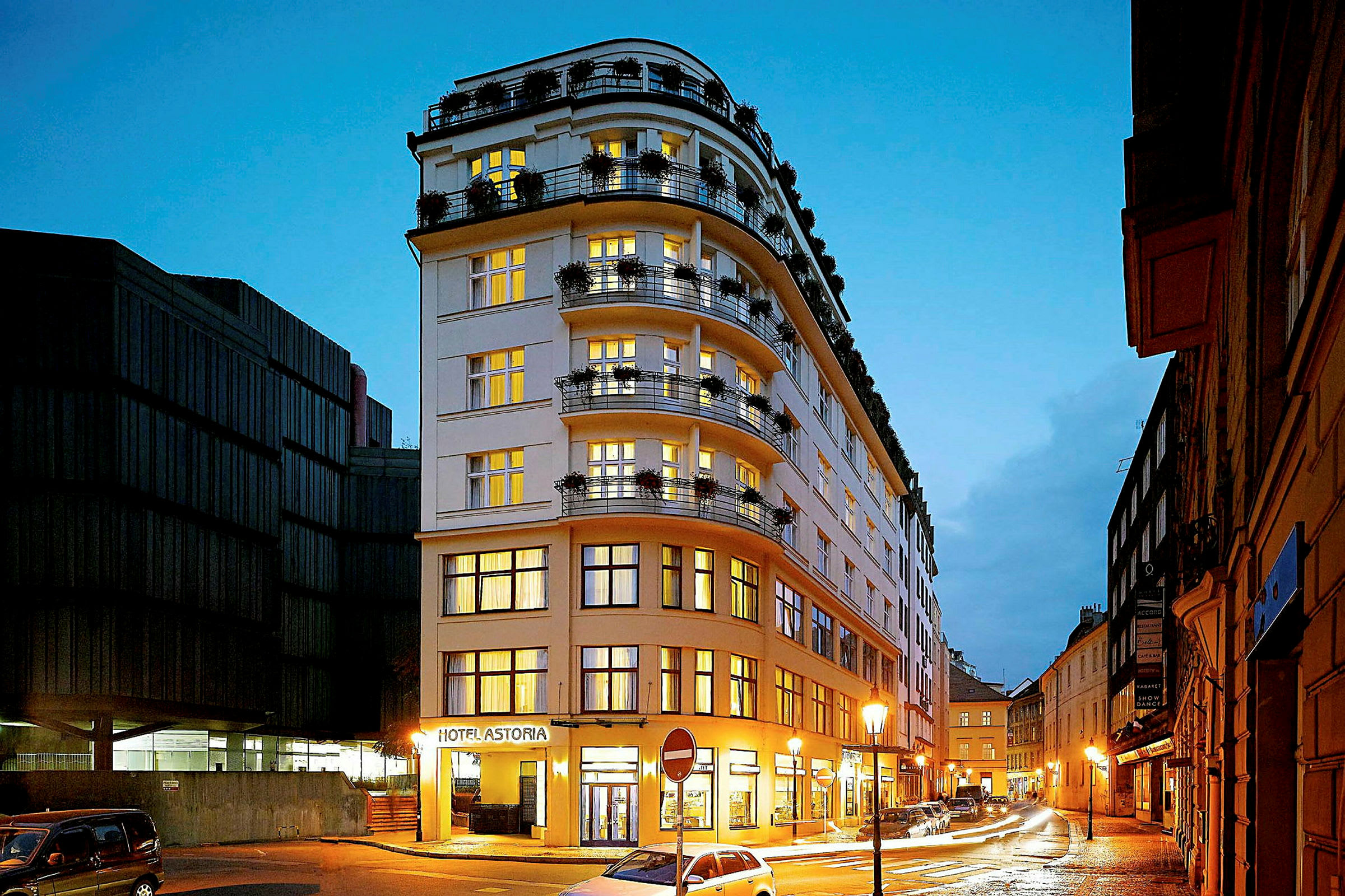 Ett hotell med namnet Hotel Astoria, beläget vid en vägsträcka med gatubelysning i en stadsmiljö. (AI-genererad text)
