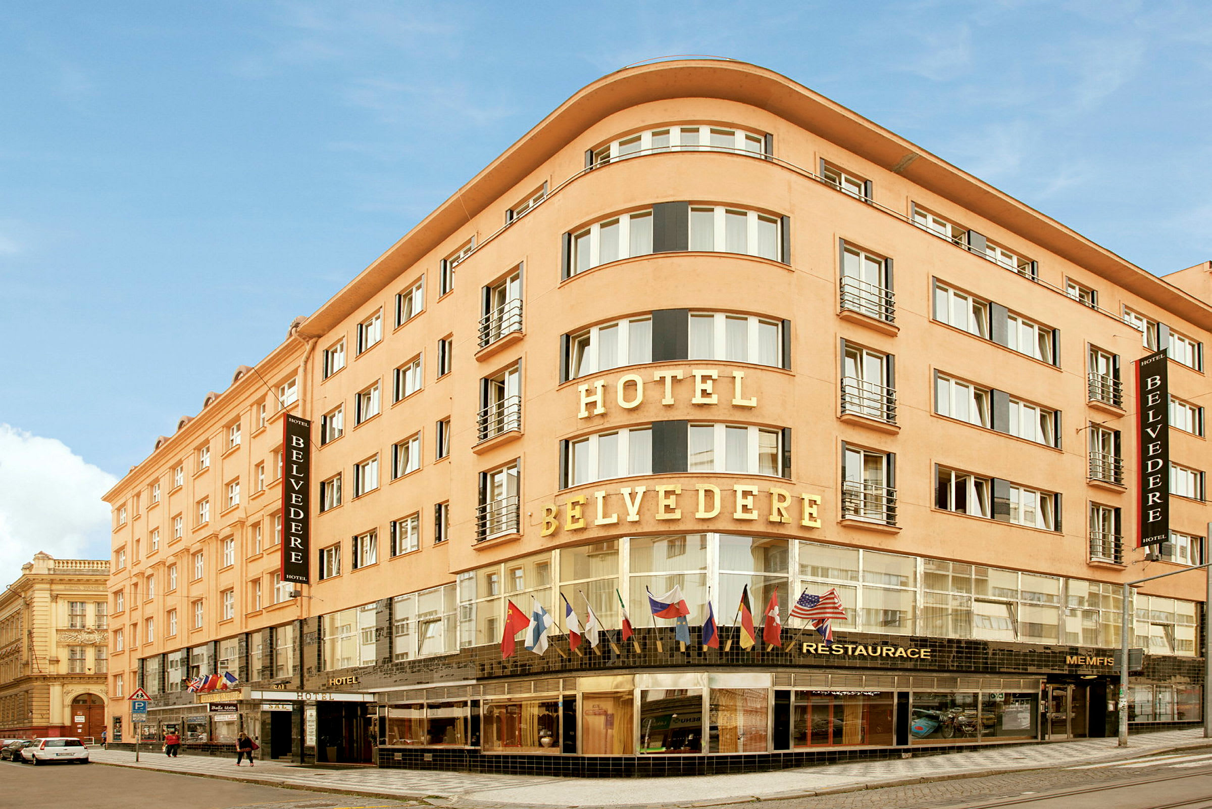 Ett hotell med namnet Hotel Belvedere, en byggnad med flera våningar och glasfönster med flaggor ovanför entrén. (AI-genererad text)