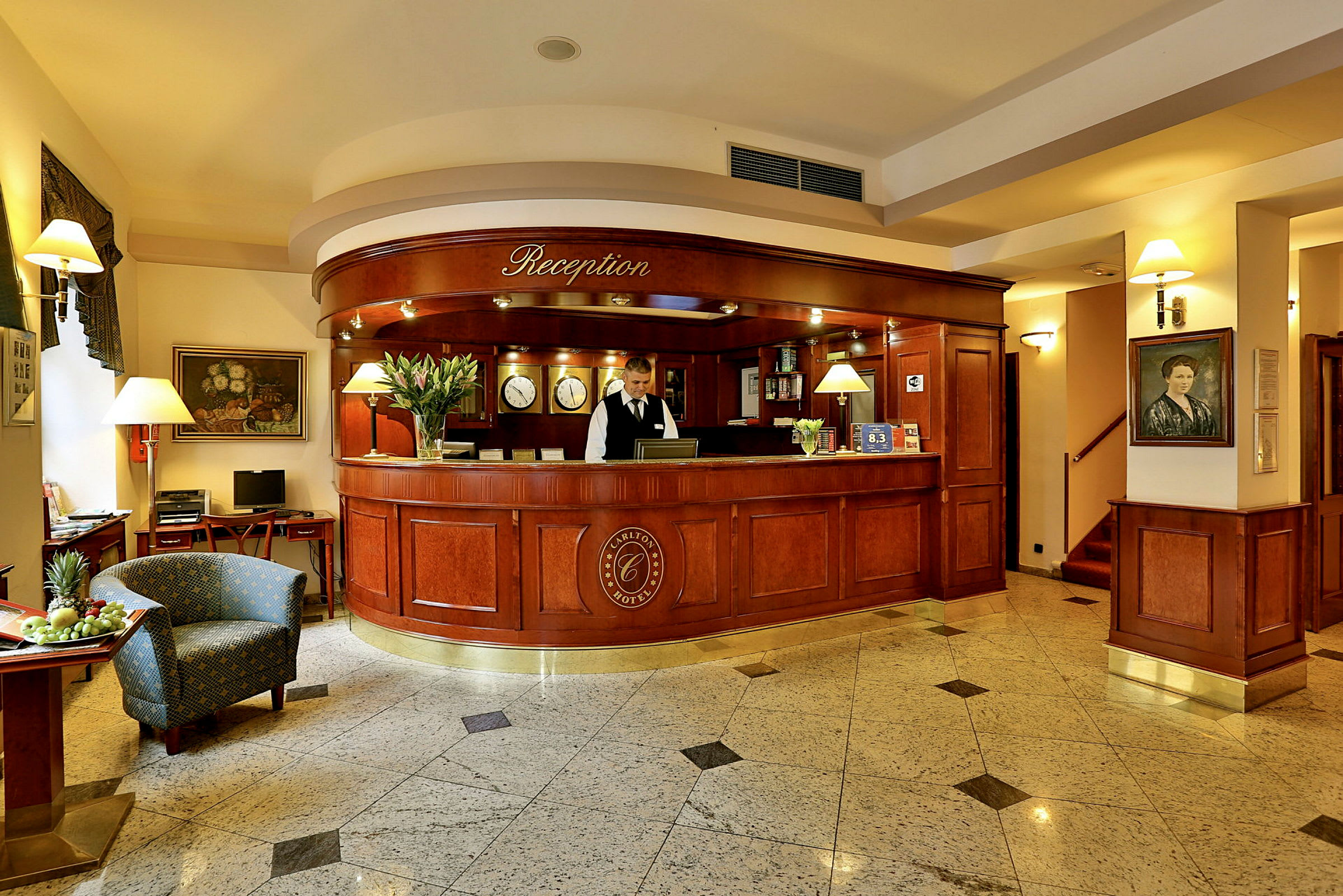 Receptionen i ett hotell med en elegant disk av trä, en receptionsanställd, en stol och en skål med frukt. (AI-genererad text)