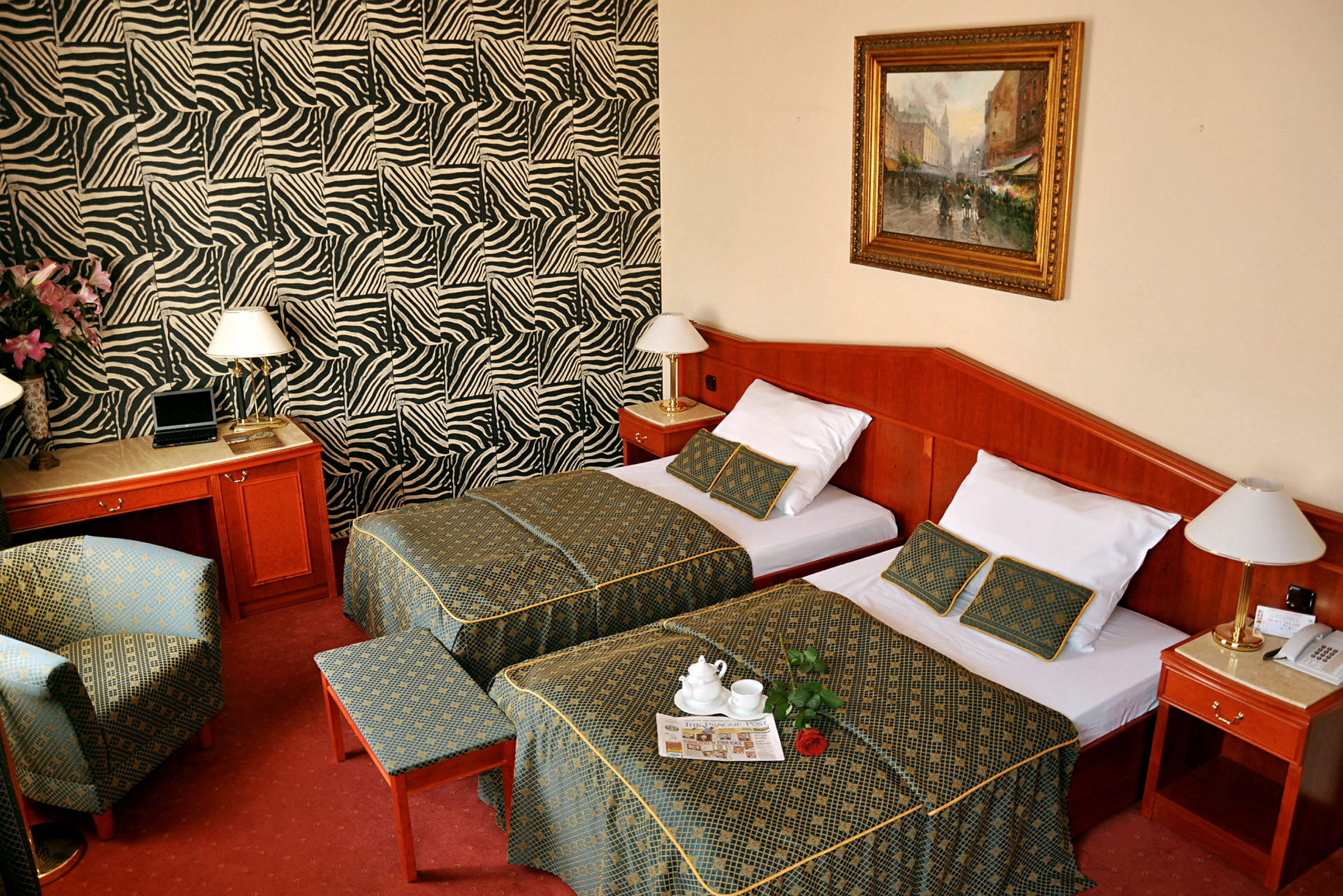 Bild av ett hotellrum med två enkelsängar, ett skrivbord, och en stol. Väggarna har zebrarandiga mönster. (AI-genererad text)