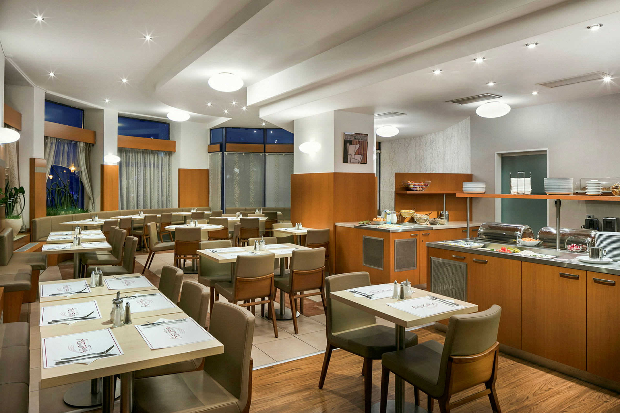 Interiör av en restaurang med bord och stolar samt en bufféservering. (AI-genererad text)