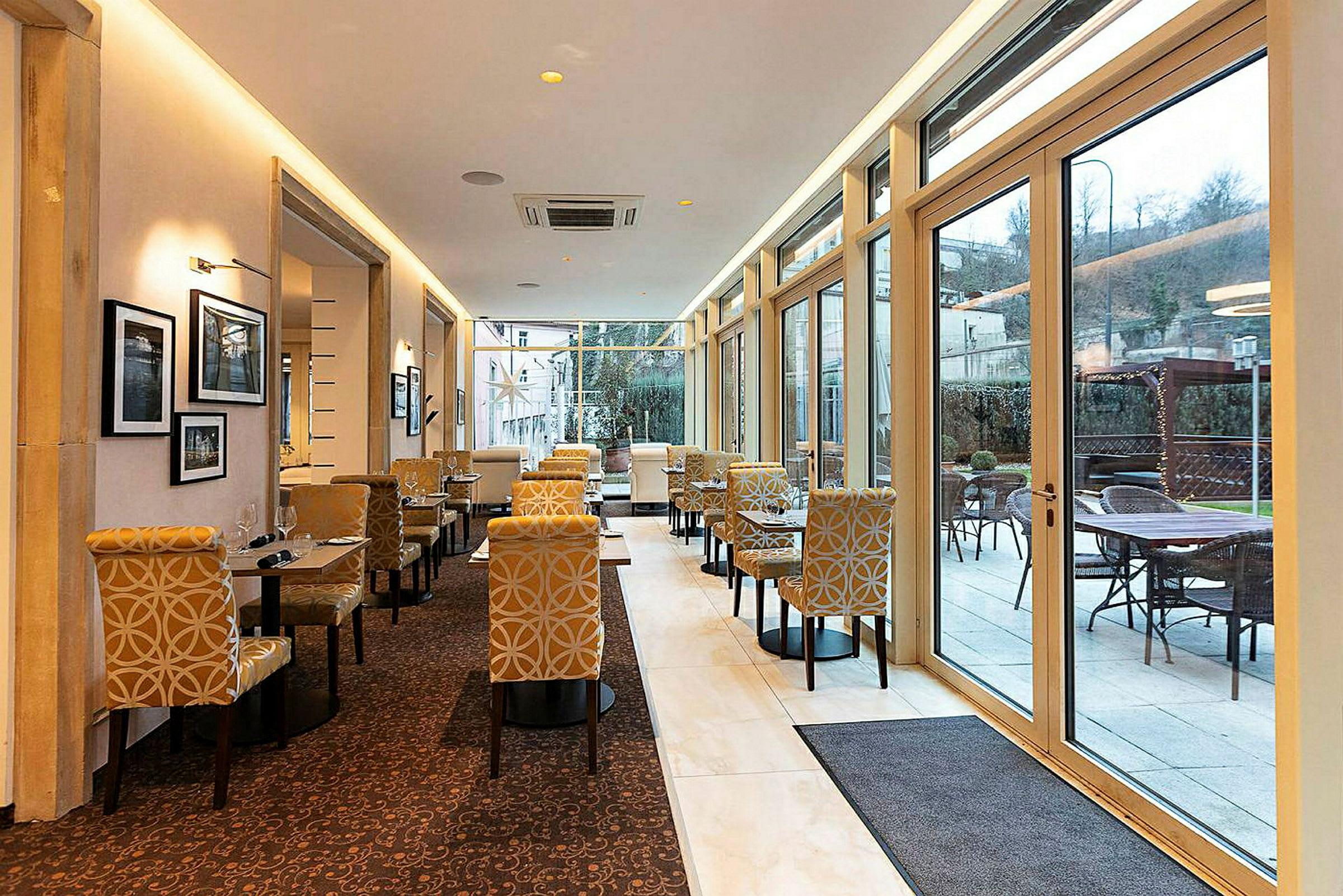 Bild på en restaurang eller café med eleganta möbler och stora fönster som släpper in rikligt med ljus. (AI-genererad text)