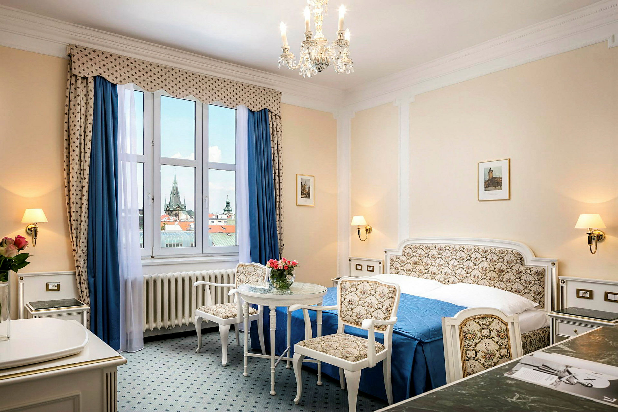 Ett hotellrum med klassisk inredning, en dubbelsäng, två stolar och ett bord samt en stor fönsterutsikt. (AI-genererad text)