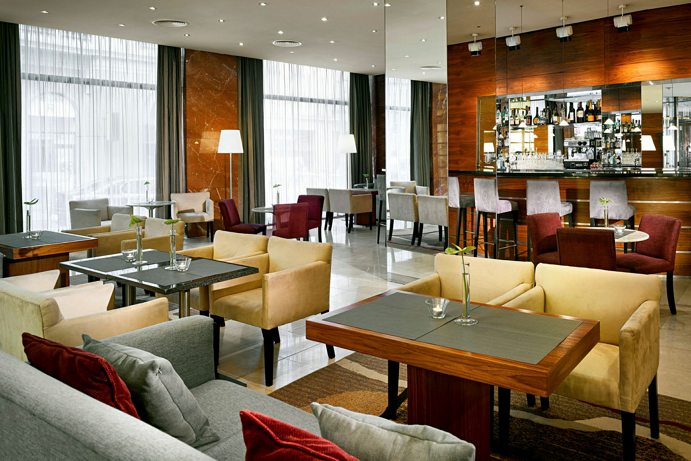 En modern hotellbar med sittmöbler och bord samt en bardisk med stolar. (AI-genererad text)