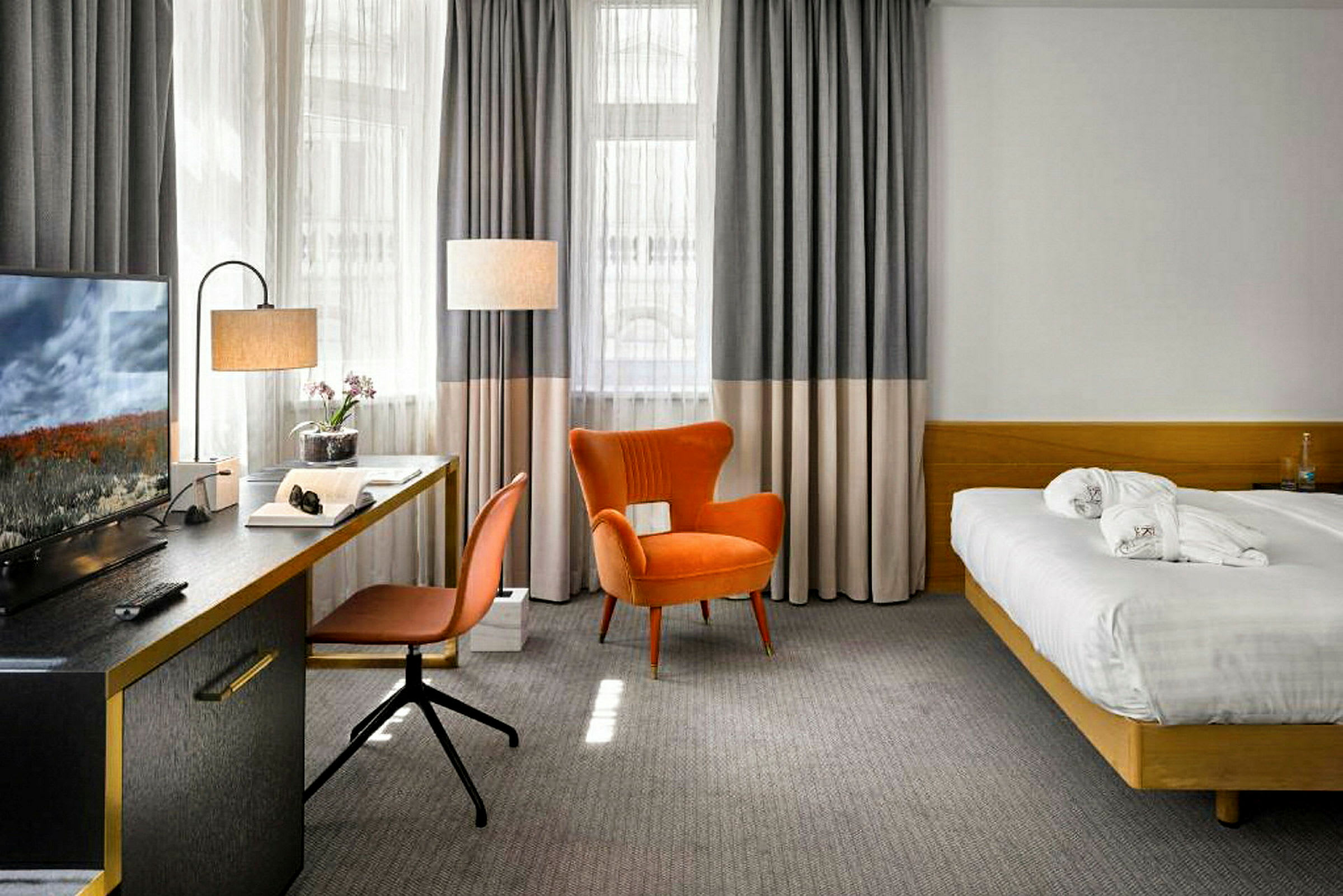 Ett hotellrum med en säng, skrivbord, stol och fåtölj. (AI-genererad text)