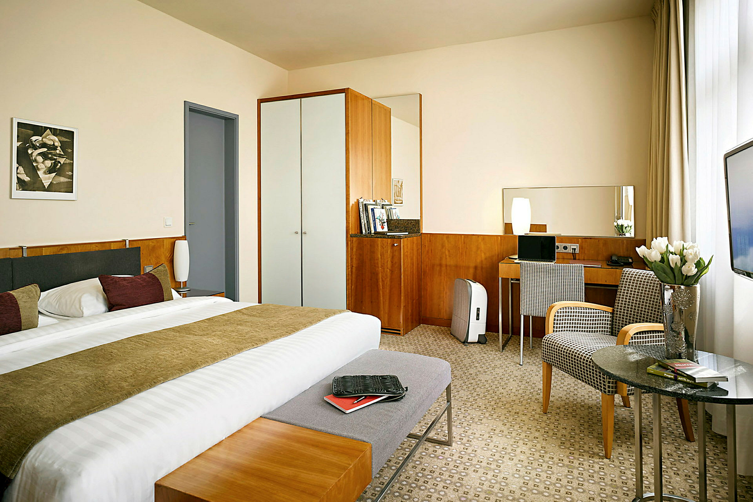 Ett hotellrum med en dubbelsäng, skrivbord, garderob och sittmöbler. (AI-genererad text)