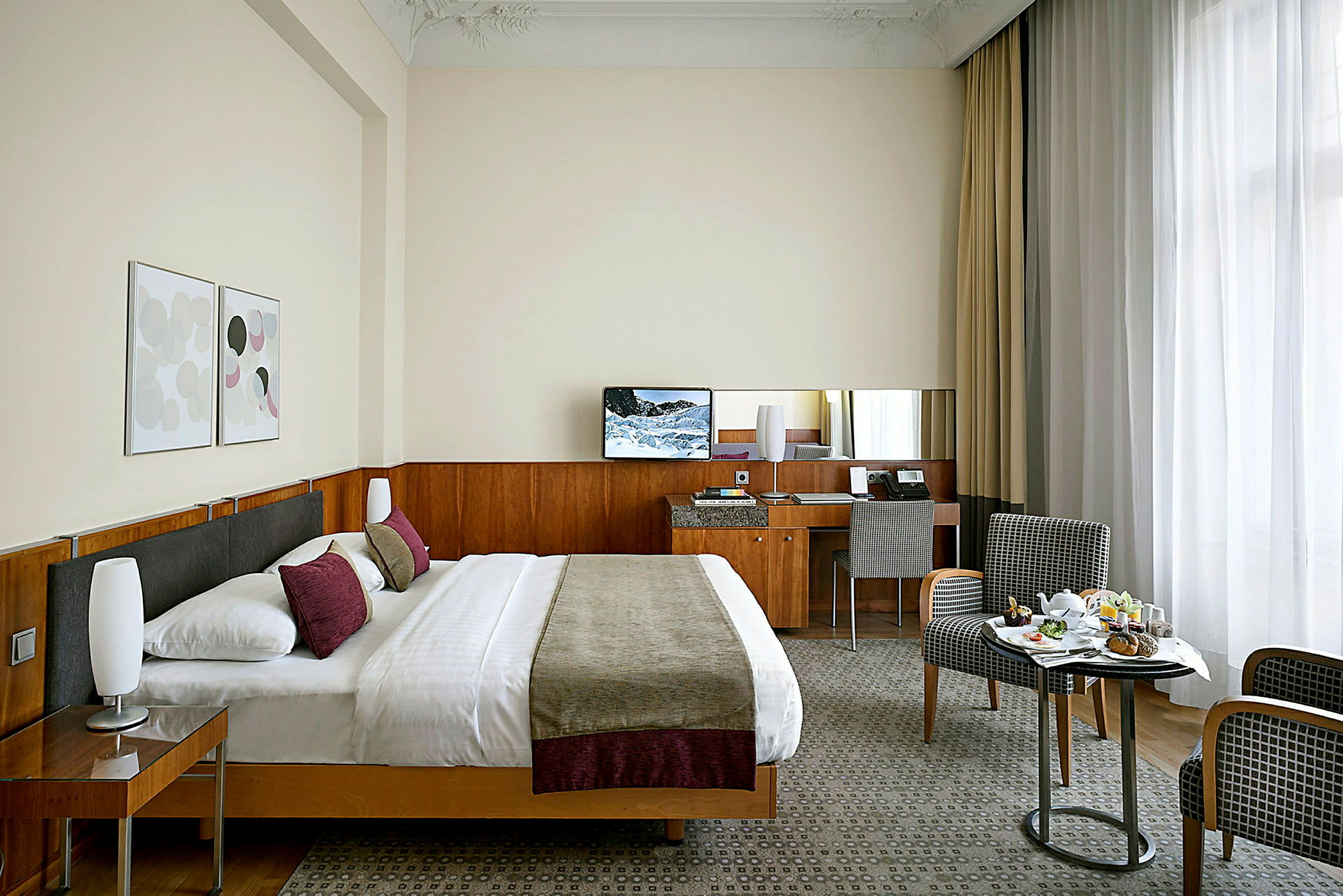 Ett hotellrum med en dubbelsäng, ett skrivbord, två stolar och en måltid serverad på ett mindre bord. (AI-genererad text)