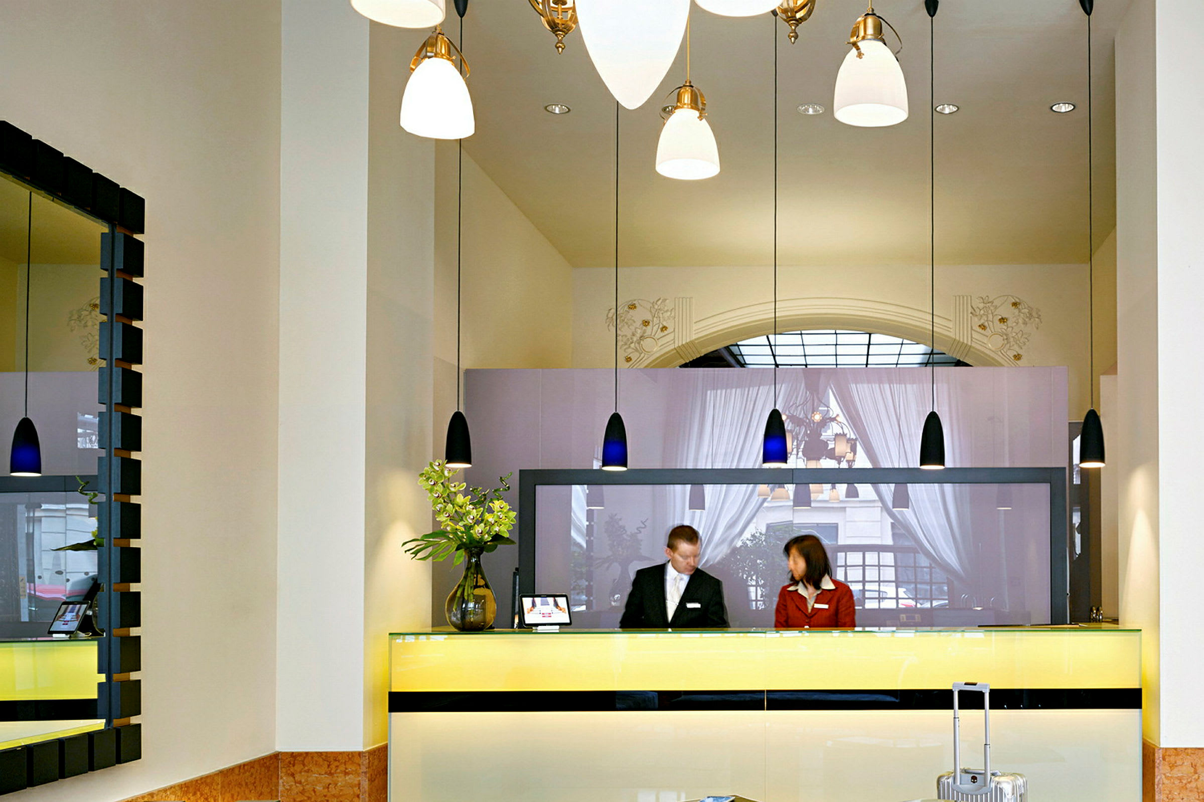 Reception med två personer bakom en gul disk i en hotellobby. (AI-genererad text)