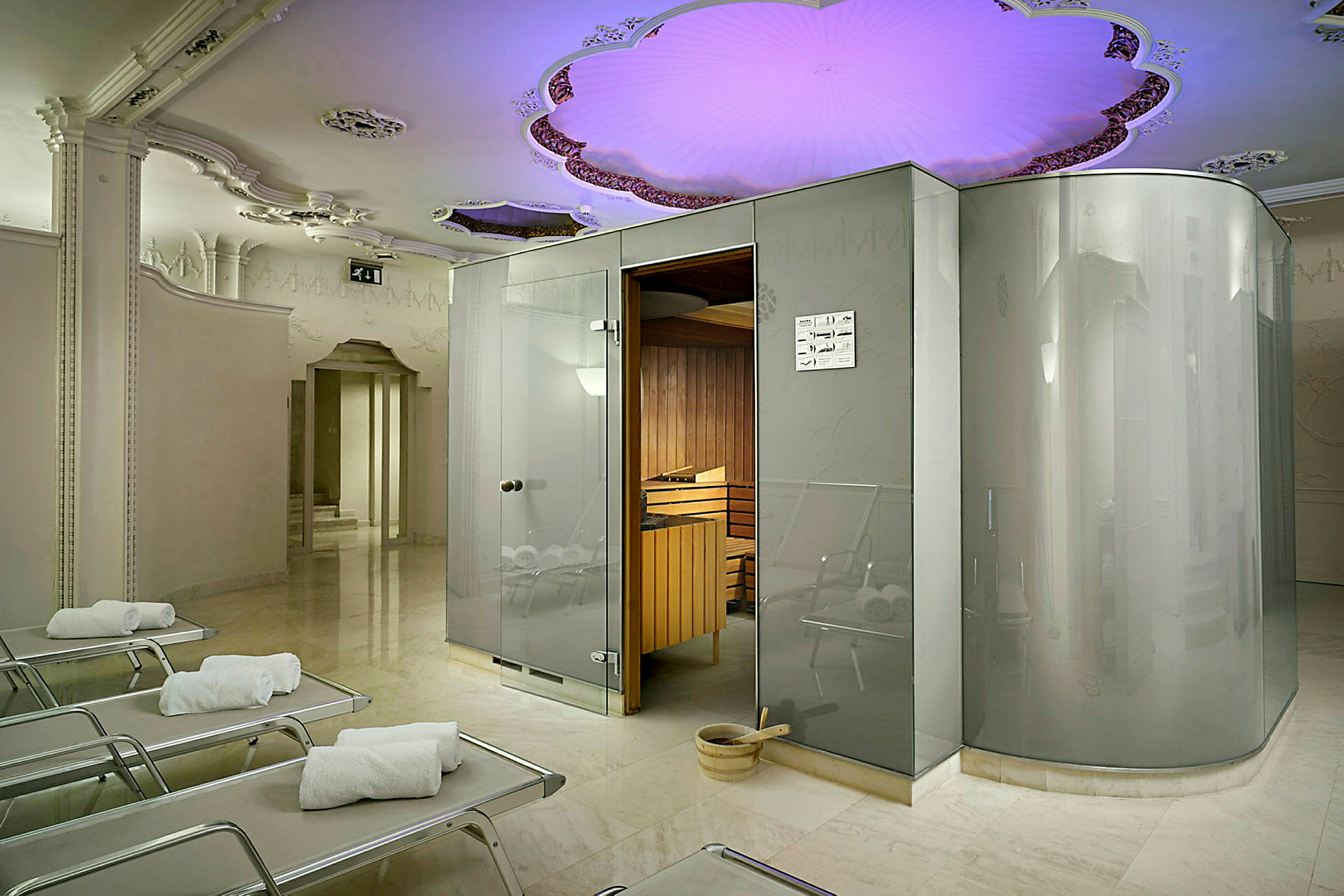 Bilden visar ett modernt spa med en bastu och loungemöbler. Taket är dekorerat med färgad belysning. (AI-genererad text)