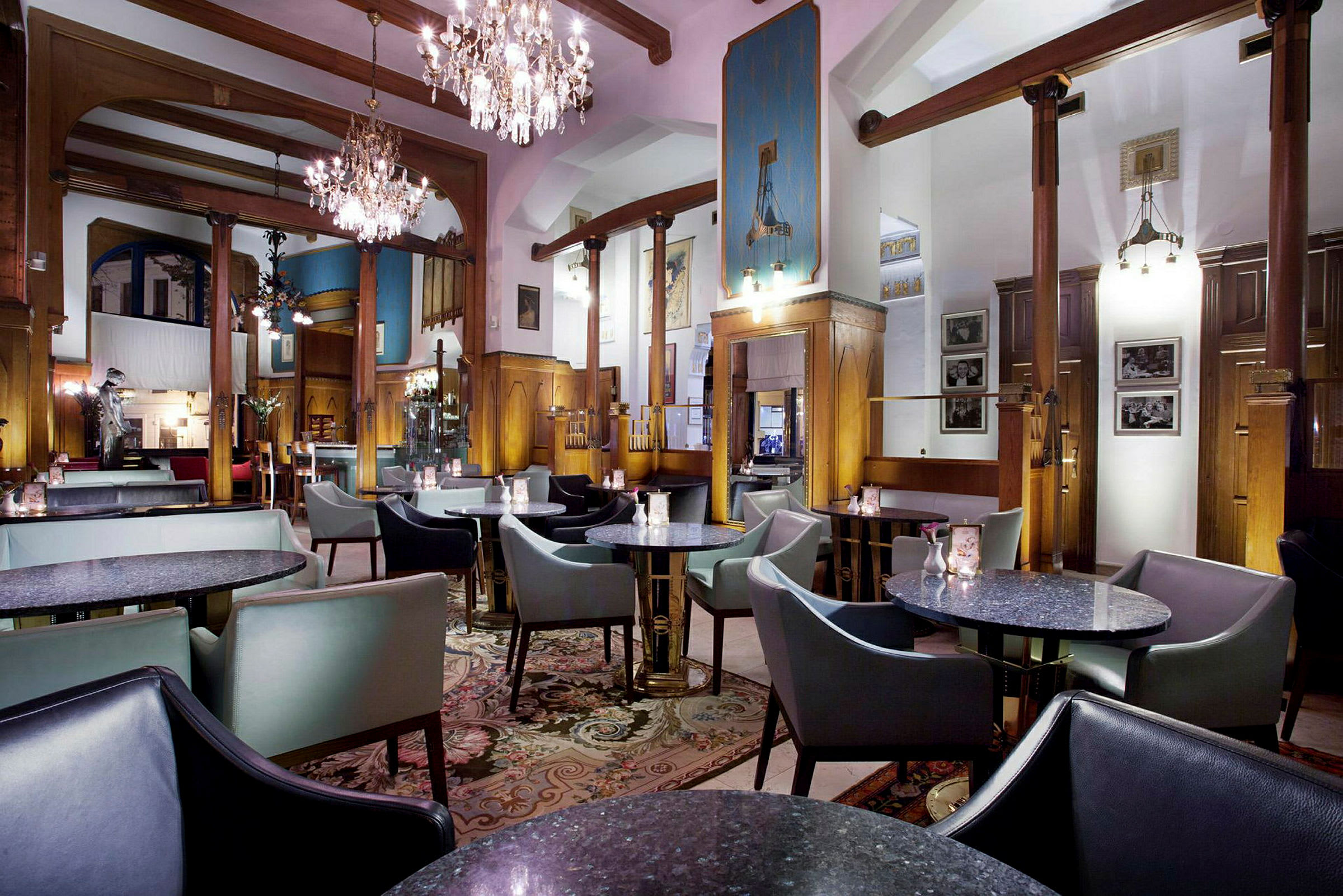 Ett elegant inrett kafé eller restaurang med runda bord, stoppade stolar och ljuskronor i taket. (AI-genererad text)