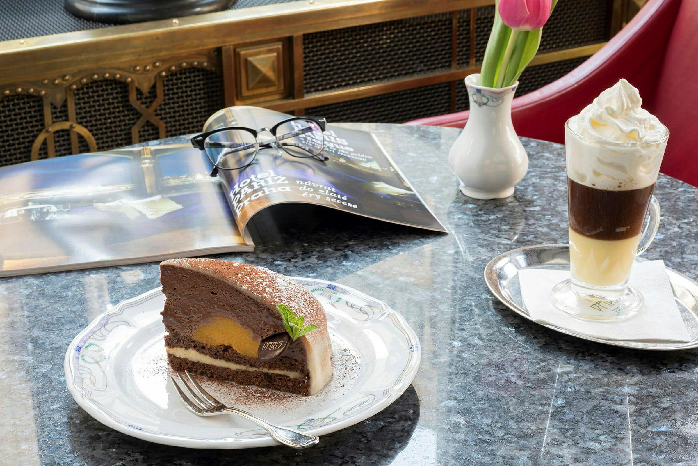 En chokladtårta på en tallrik och en glass kaffe med grädde på ett bord. (AI-genererad text)