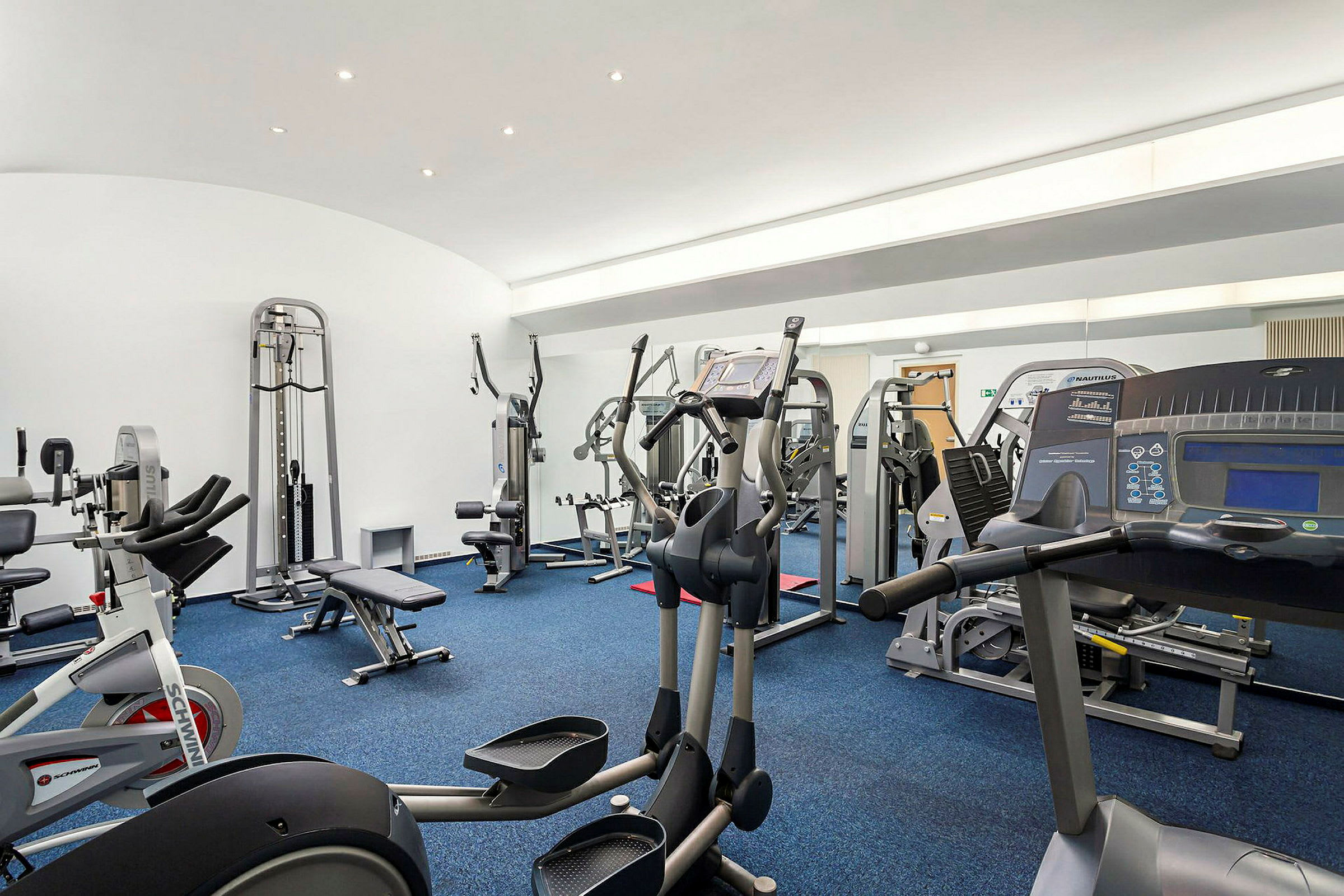 Ett gym med träningsutrustning som löpband, cyklar och gymmaskiner. (AI-genererad text)