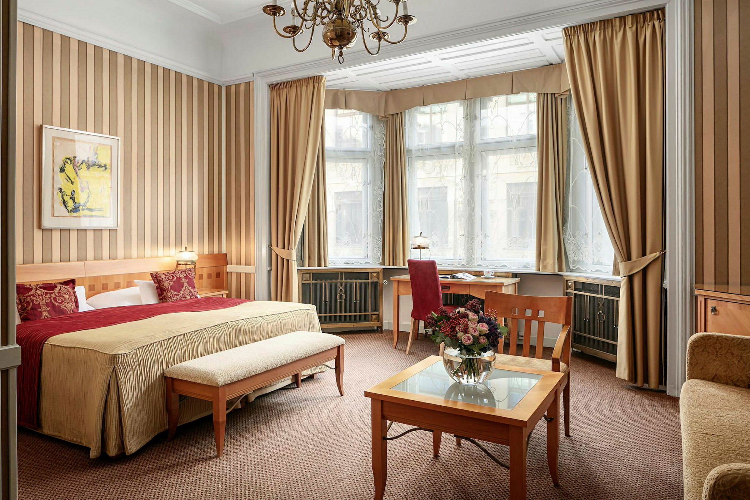 Ett hotellrum med en stor säng, en sittgrupp och ett arbetsbord vid ett stort fönster. (AI-genererad text)