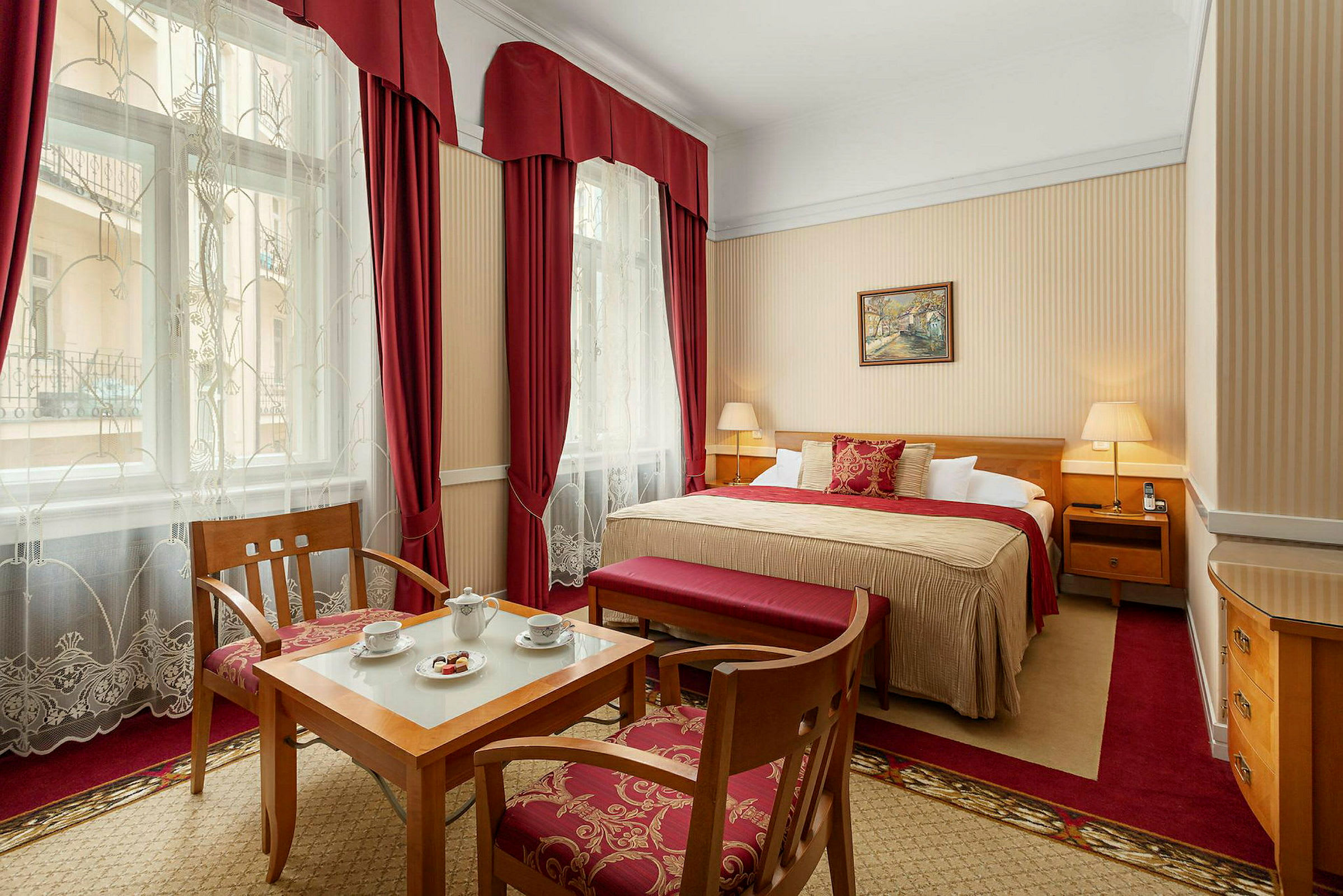 Ett elegant hotellrum med en stor säng, träinredning och röda gardiner. (AI-genererad text)