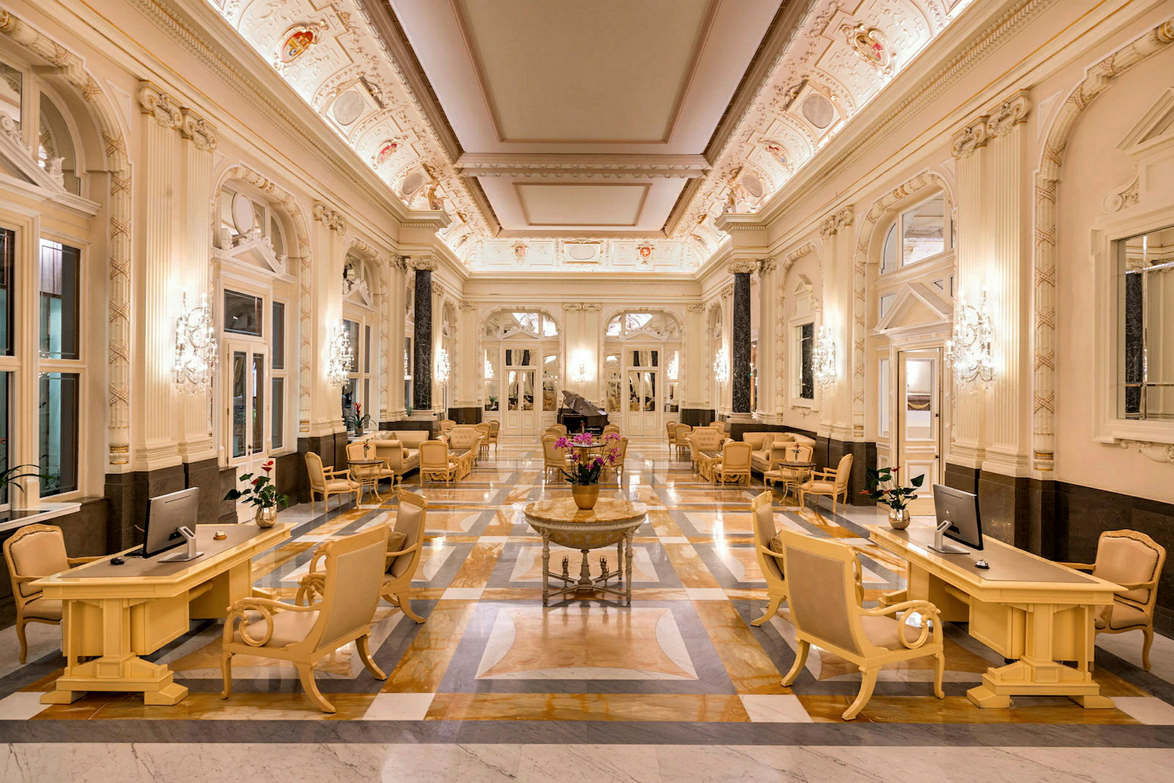 En elegant hotellobby med marmorgolv, stilfulla möbler och dekorativt utsmyckad takpanel. (AI-genererad text)