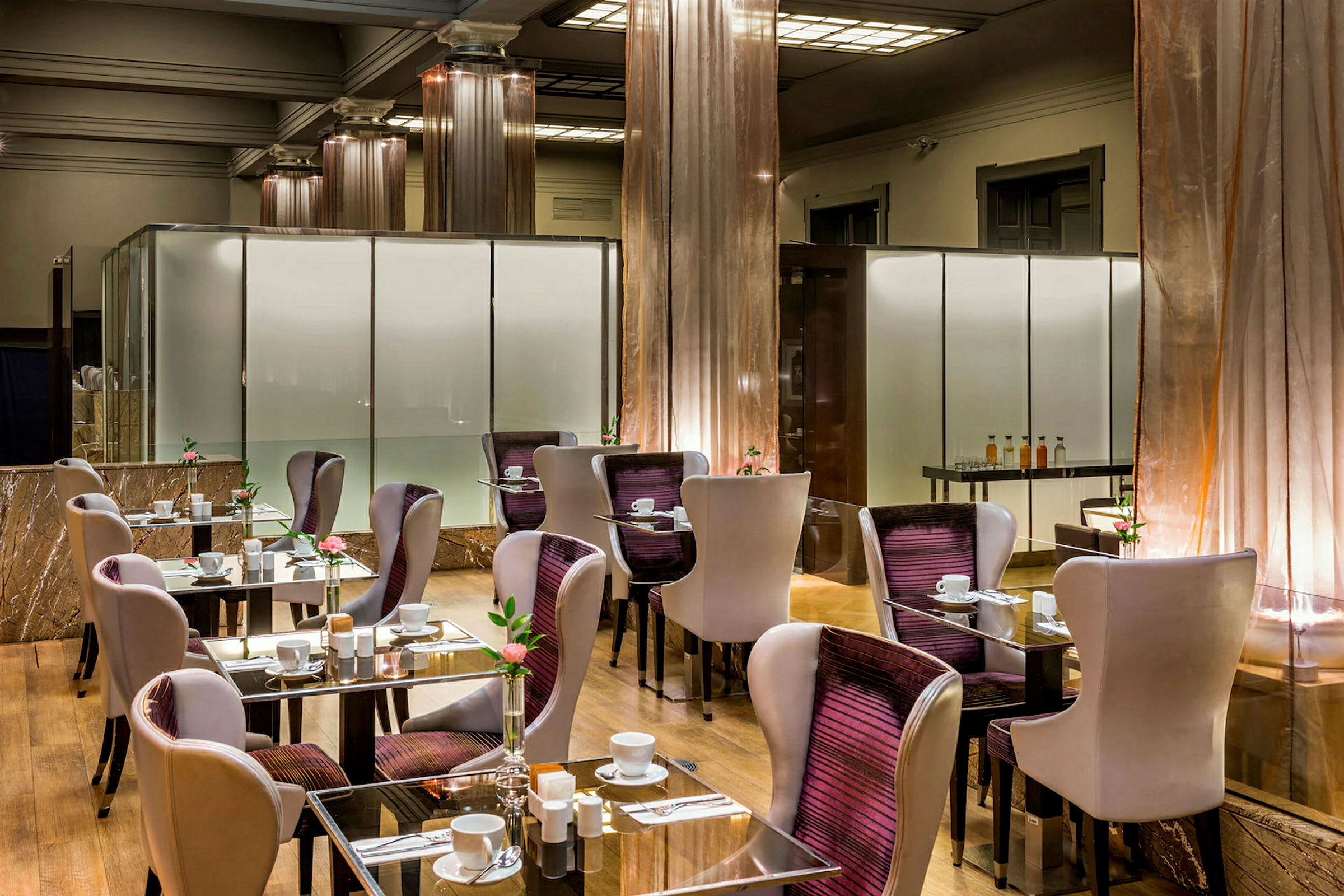 Modern restaurang med bord och stolar. Glasbord med dukning och blomdekorationer. (AI-genererad text)