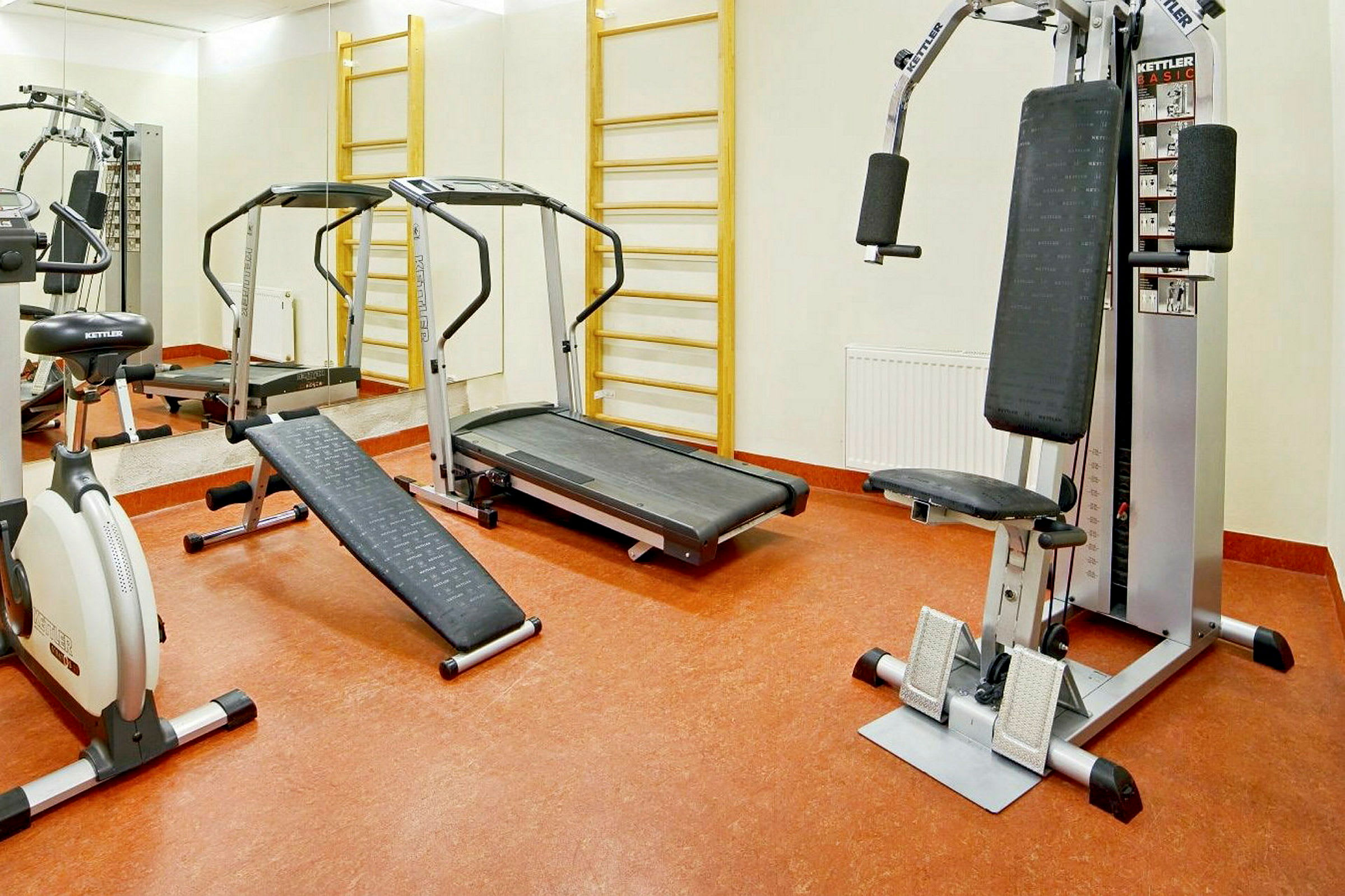Bild av ett gym med olika träningsmaskiner, inklusive ett löpband, en träningscykel och en multifunktionell träningsmaskin. (AI-genererad text)