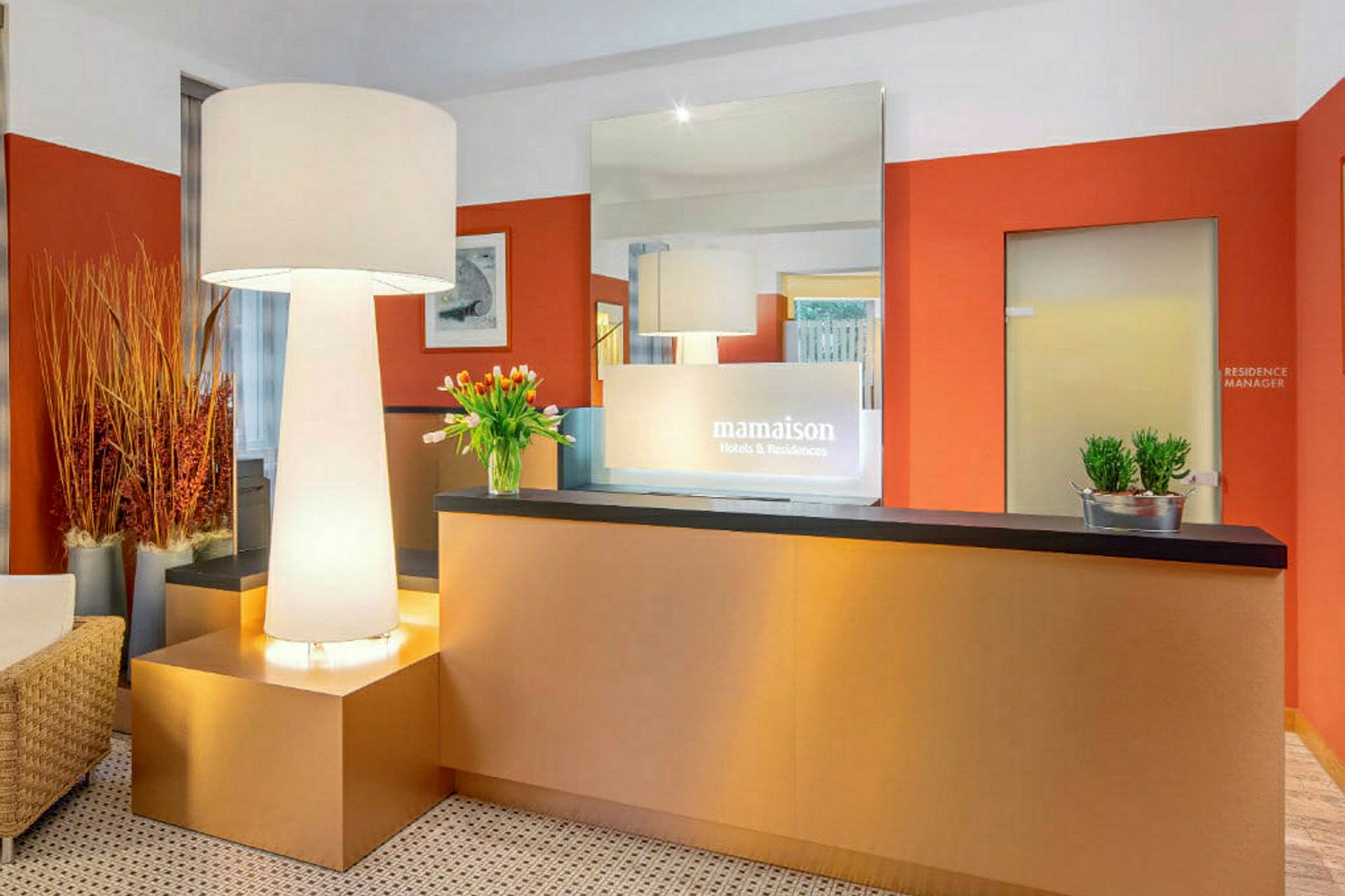 Receptionsområde med ett modernt inrett bord, en stor golvlampa och dekorationer som blommor och växter. (AI-genererad text)