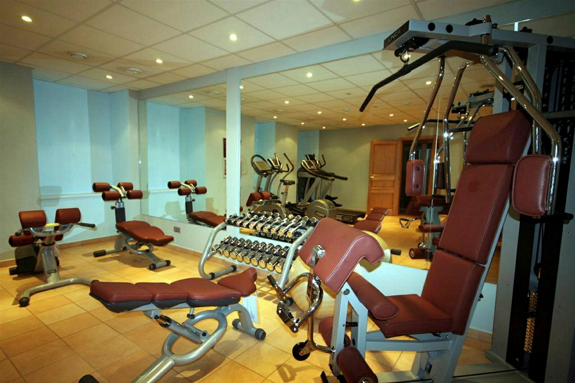 Bild av ett gym med träningsmaskiner, hantlar och träningsbänkar. (AI-genererad text)