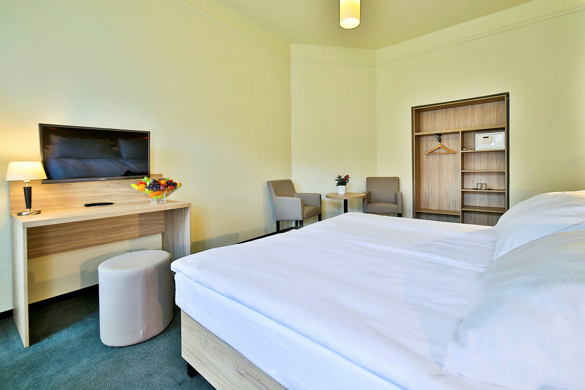 Ett hotellrum med säng, skrivbord, stol och en garderob. (AI-genererad text)