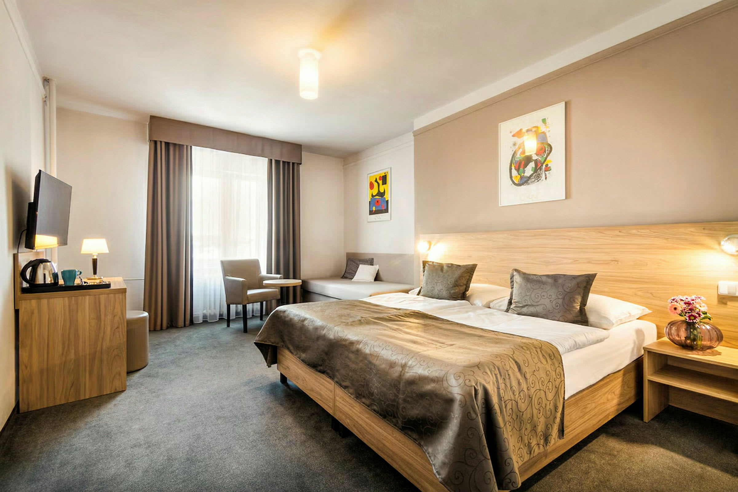 Ett hotellrum med en stor dubbelsäng, ett bord med två stolar och en väggmonterad TV. (AI-genererad text)