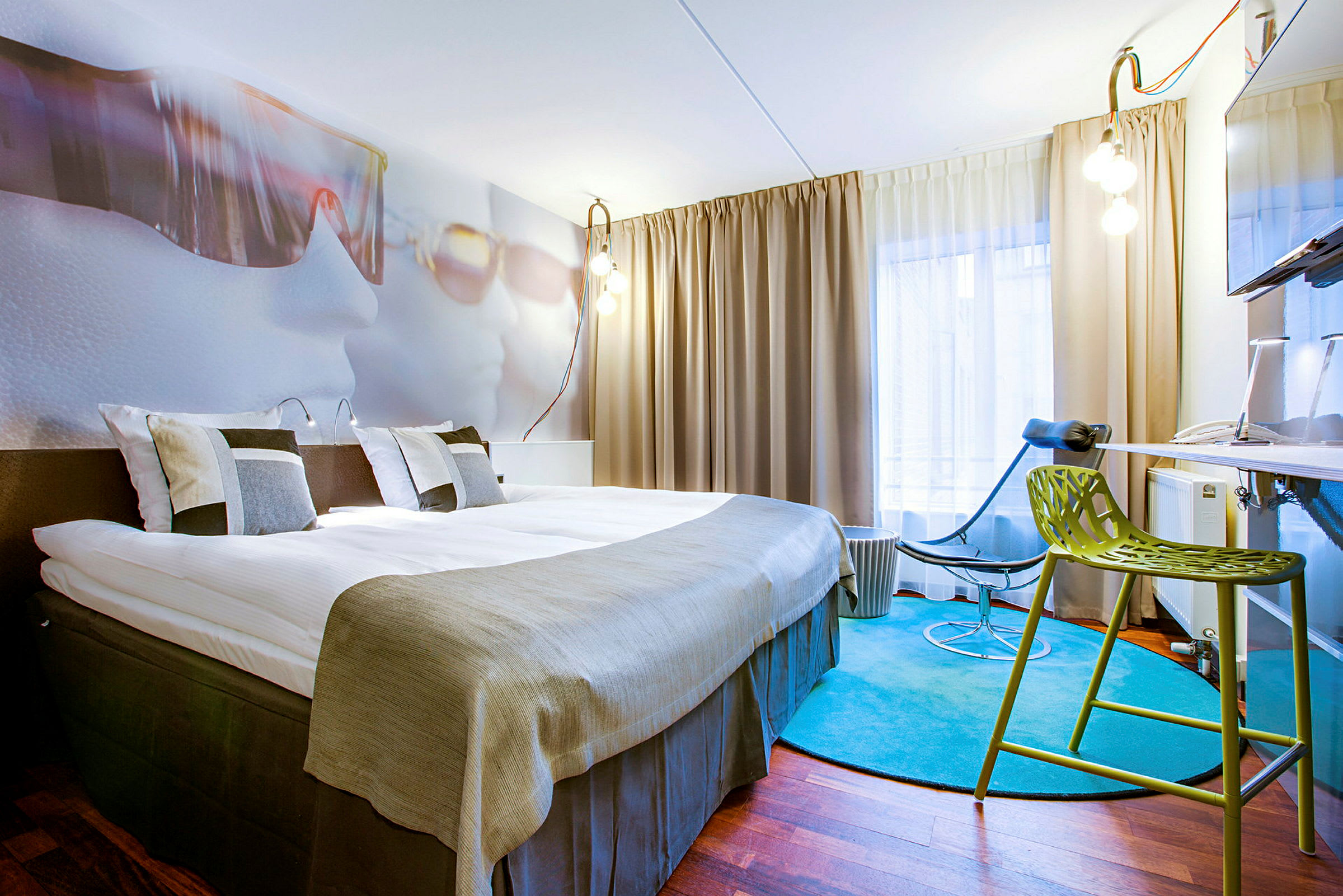 Ett hotellrum med en stor säng, moderna möbler och en färgglad matta. (AI-genererad text)