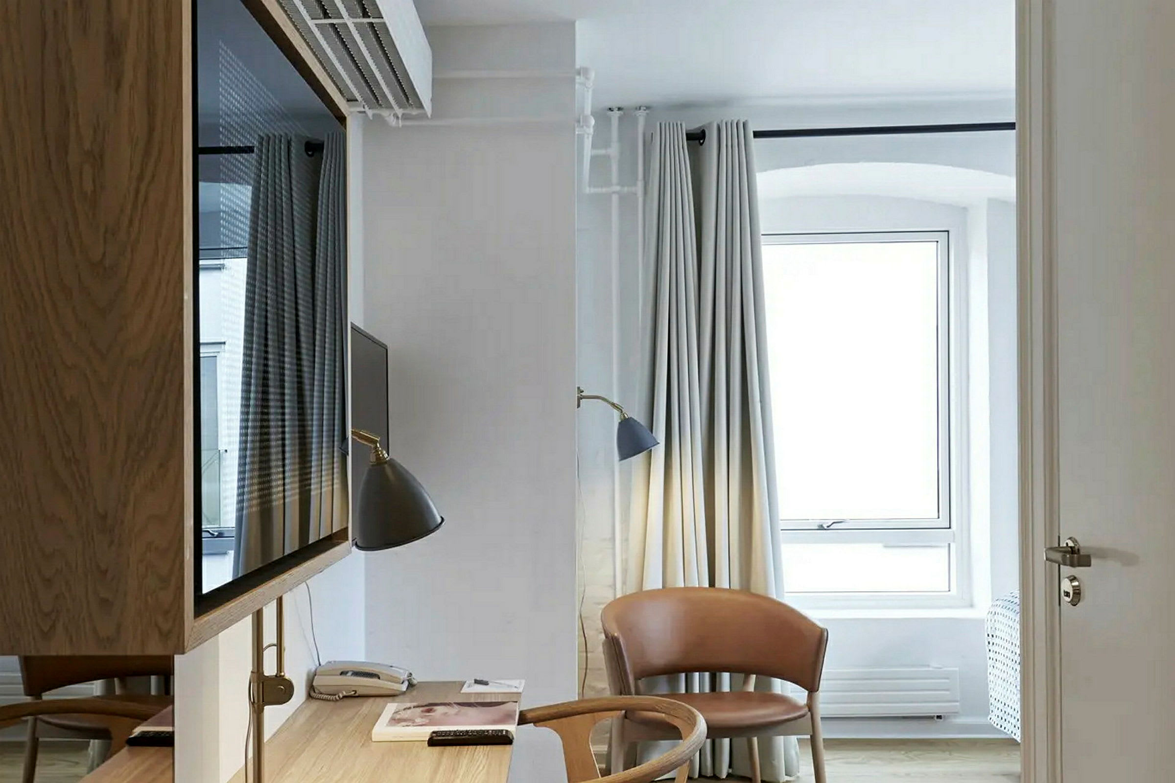 Ett ljust hotellrum med skrivbord, stol och fönster. (AI-genererad text)