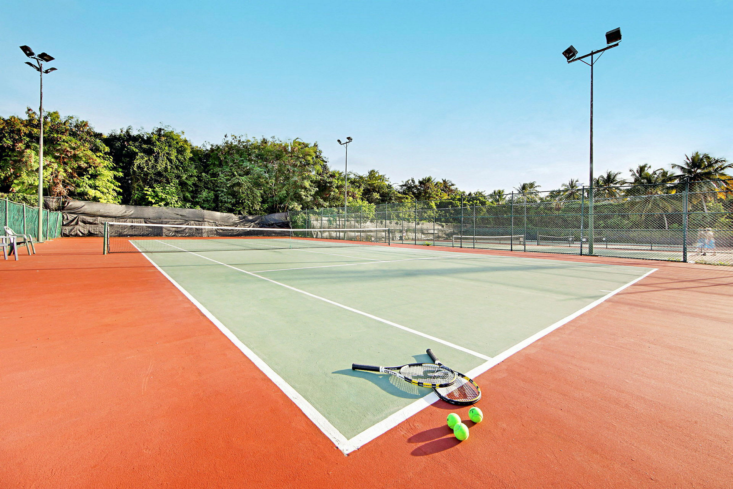 En tennisbana med rack och bollar liggande på marken. (AI-genererad text)