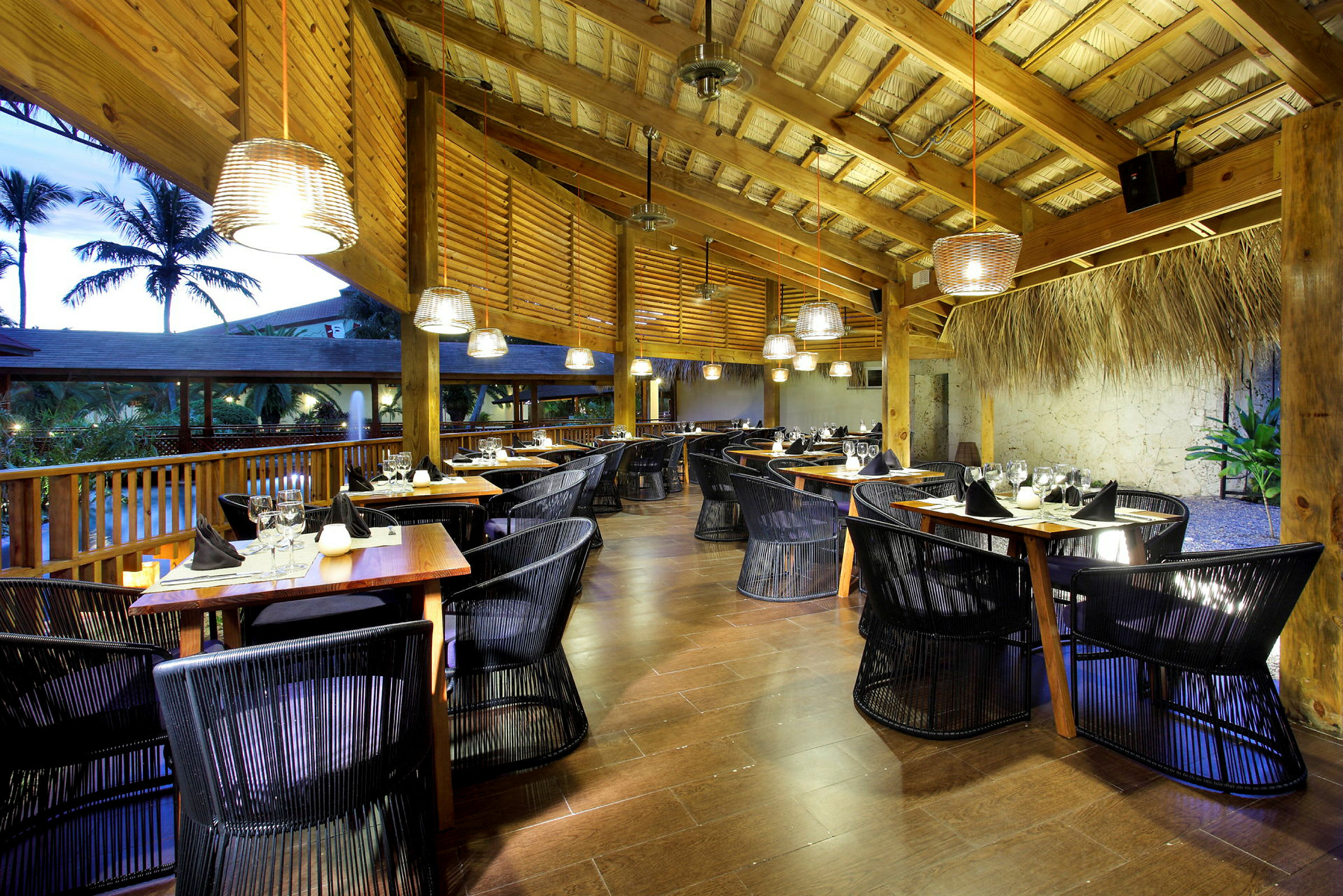 En träbyggd restaurang med dukade bord och moderna stolar. Miljön har elegant belysning och tak av naturmaterial. (AI-genererad text)