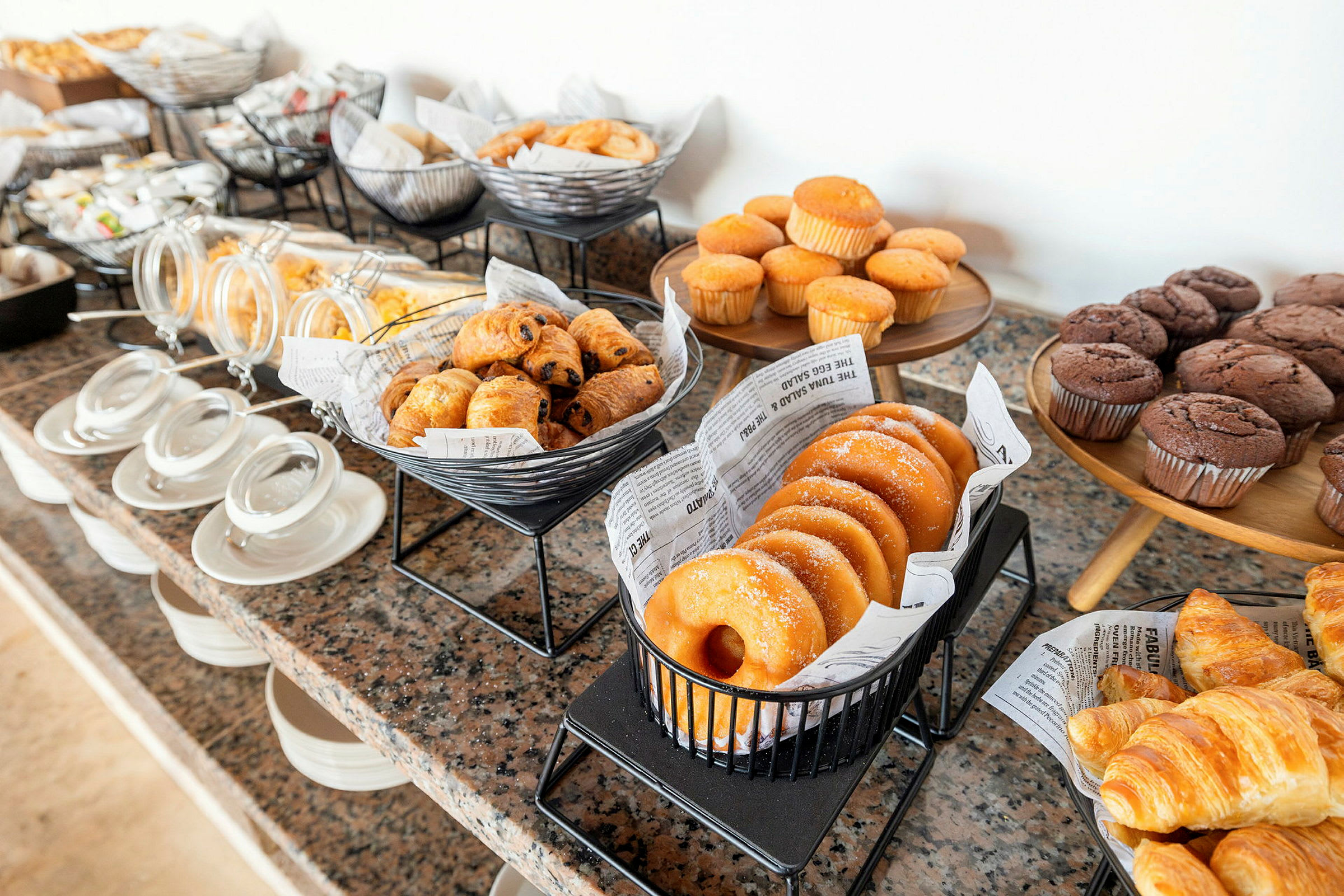 En buffé med olika bakverk som muffins, croissanter och munkar. (AI-genererad text)