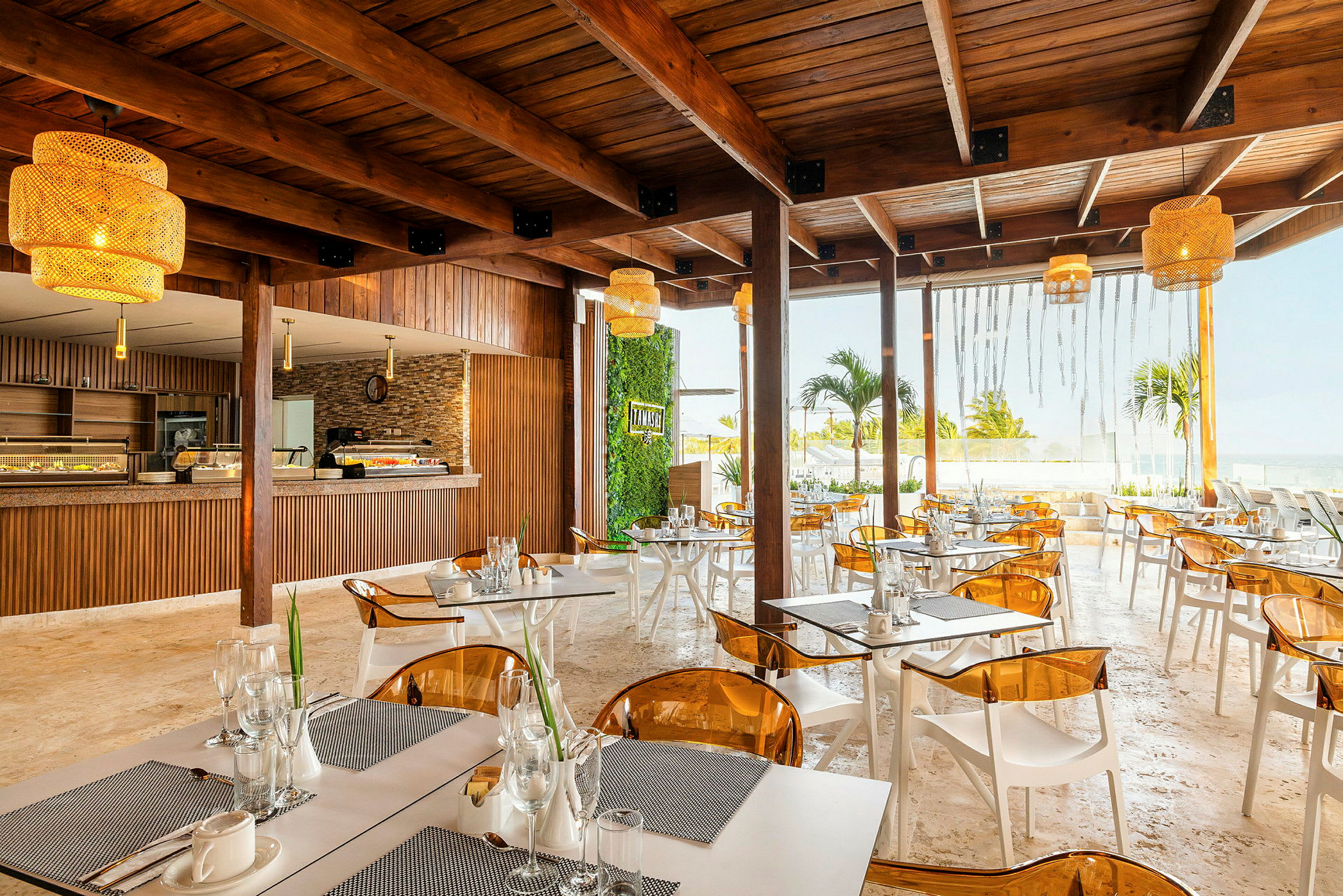En modern restaurang med trämöbler, gula lampor och utsikt över havet. (AI-genererad text)