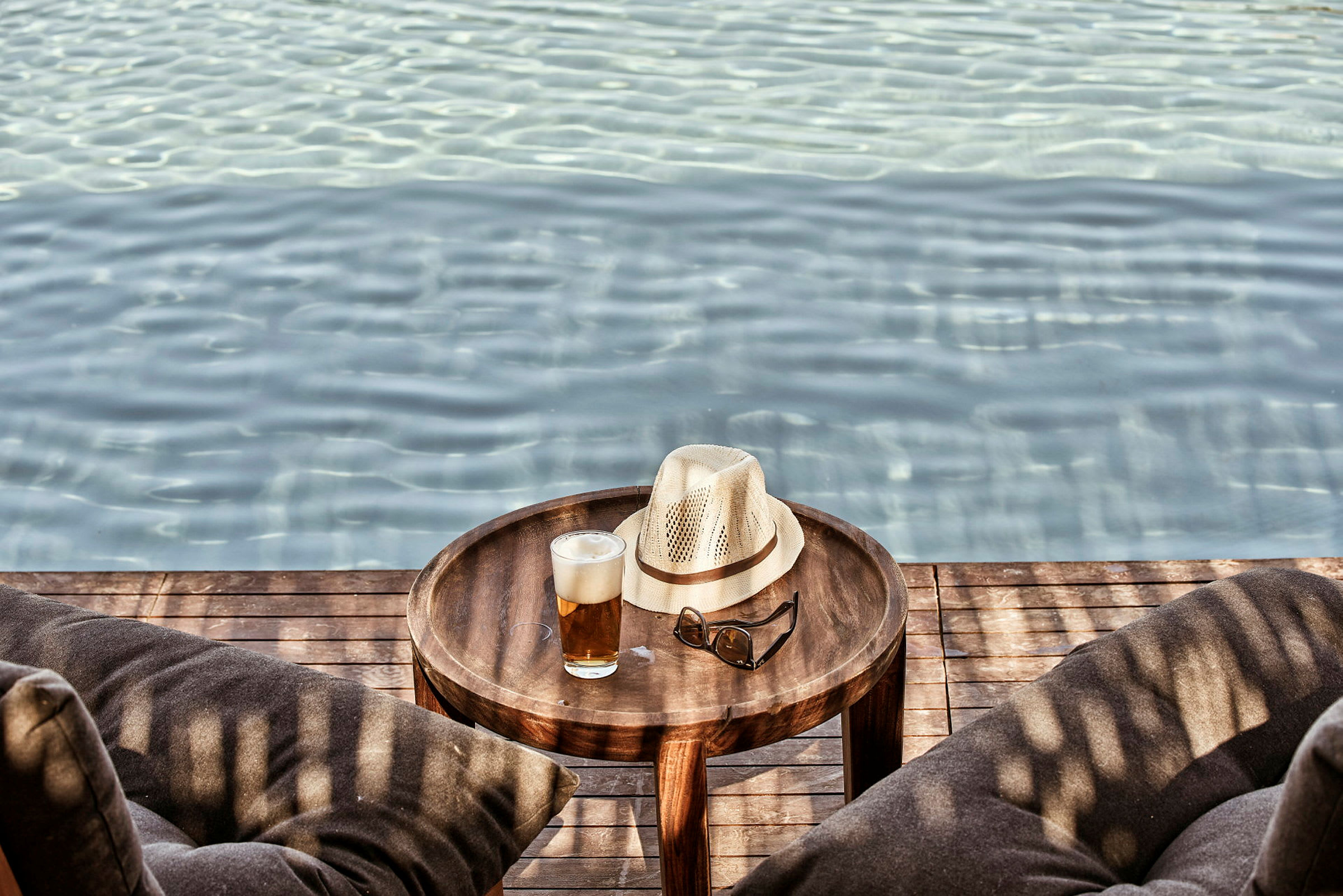 Ett bord vid en pool med hatt, solglasögon och ett glas dryck. (AI-genererad text)