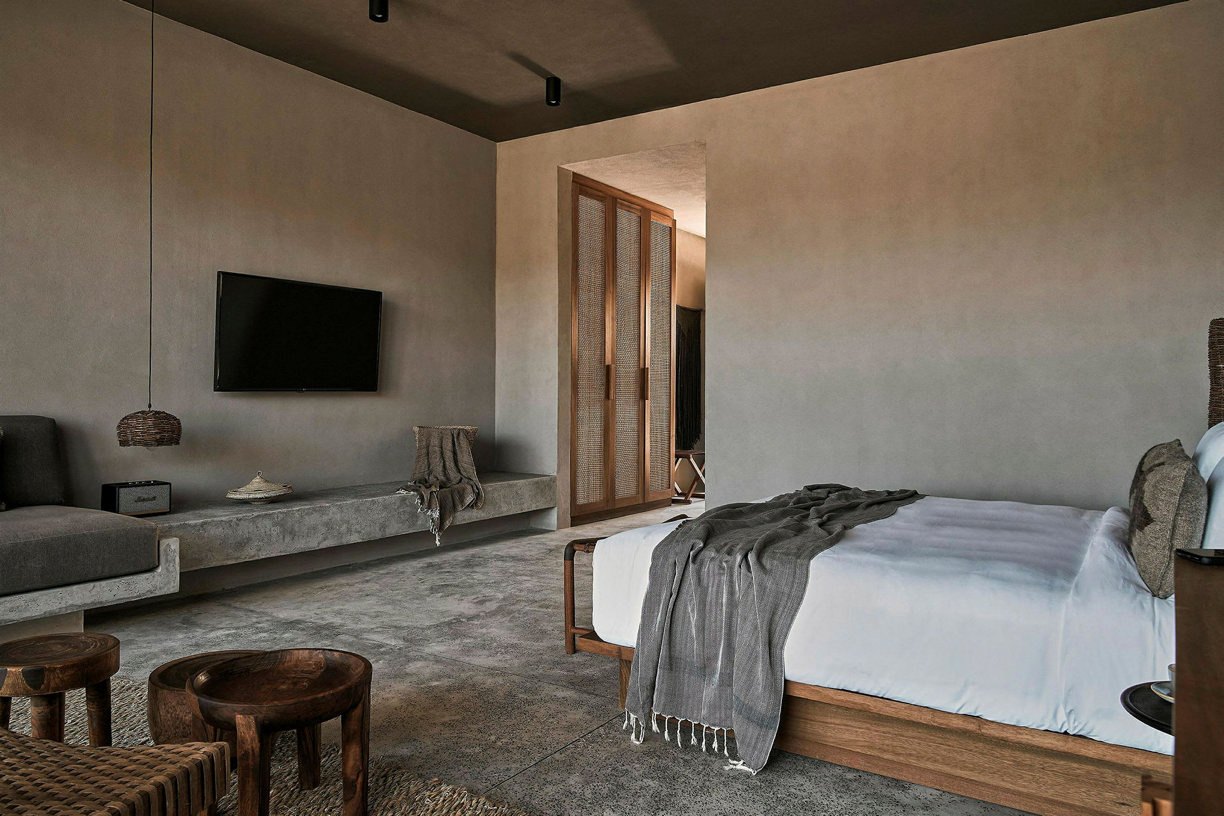 Ett modernt designat hotellrum med TV, säng, soffområde och entré till annan del av rummet. (AI-genererad text)