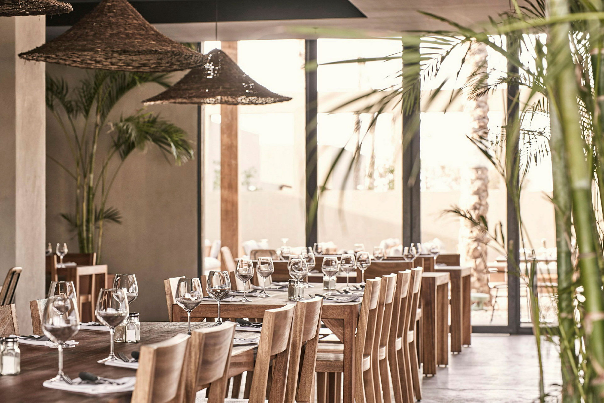 Interiör av en restaurang med träbord, stolar och dekorerade med glas och bestick. (AI-genererad text)
