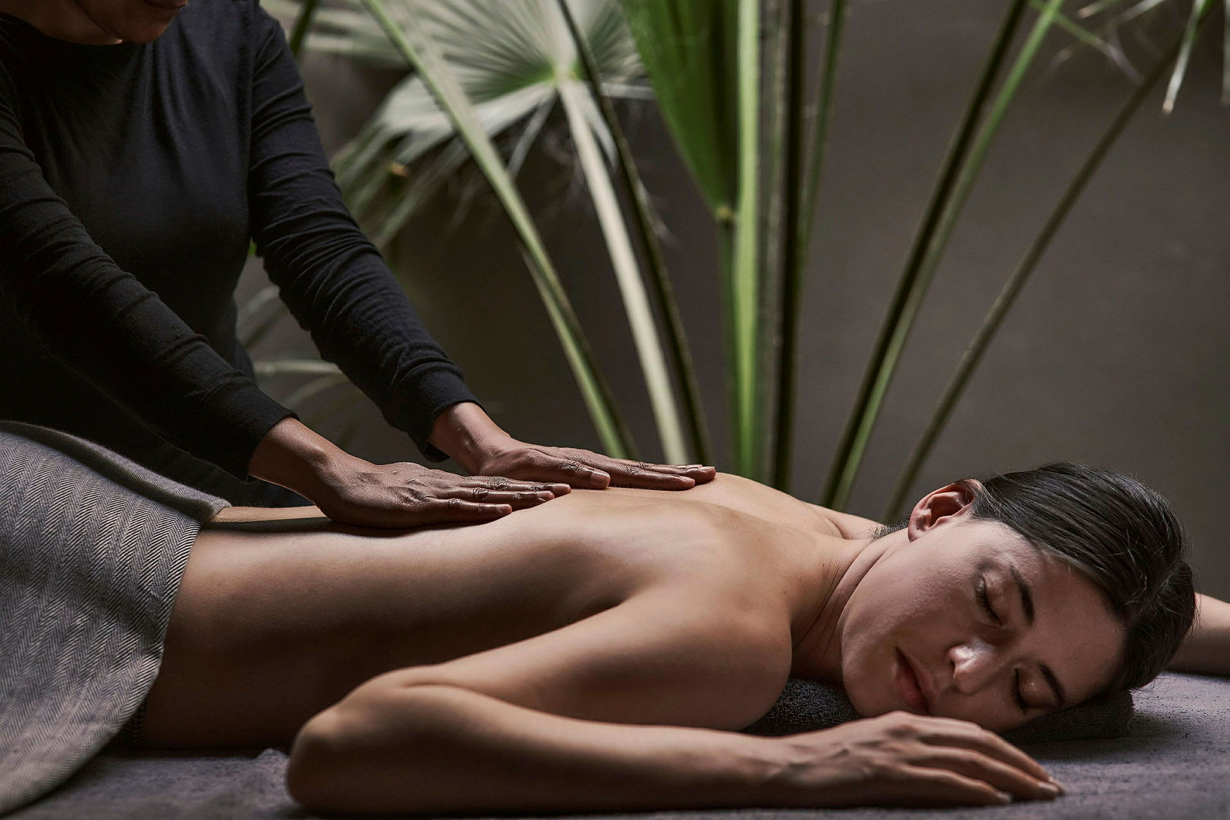 En person får en ryggmassage med omslutande växter i bakgrunden. (AI-genererad text)