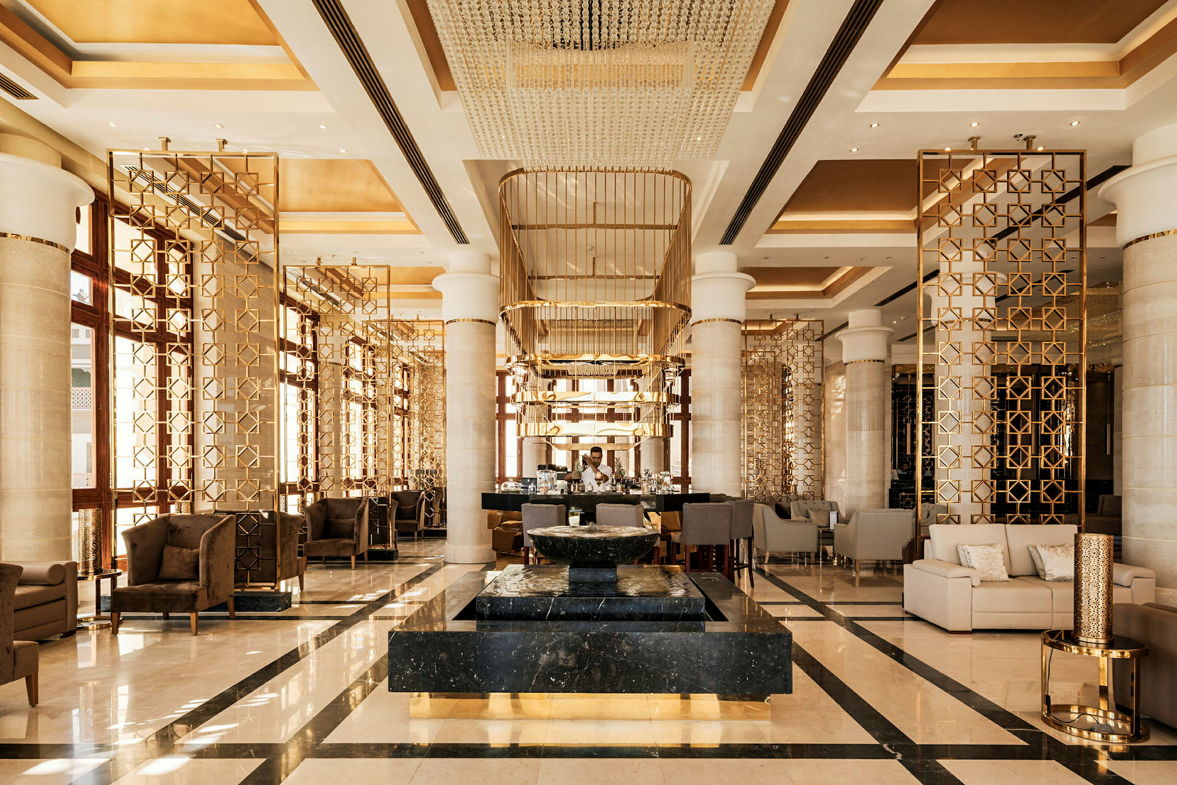 Ett elegant hotellobby med moderna möbler, gyllene dekorationer och en centralt placerad marmordetalj. (AI-genererad text)