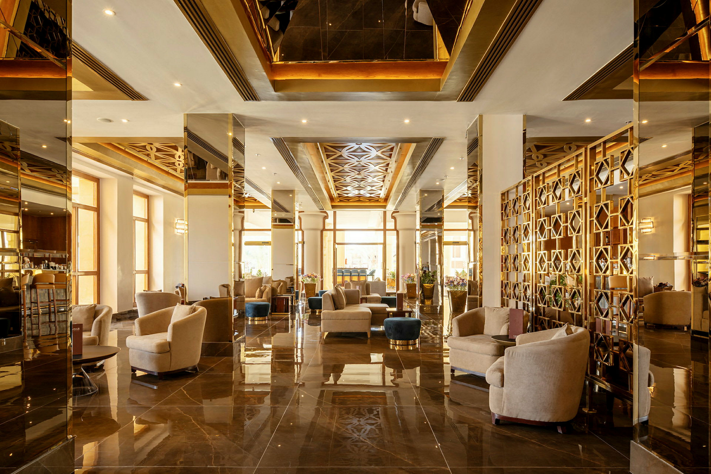 Elegant hotellobby med sittgrupper, dekorerad med speglar och guldaccentuerade detaljer. (AI-genererad text)
