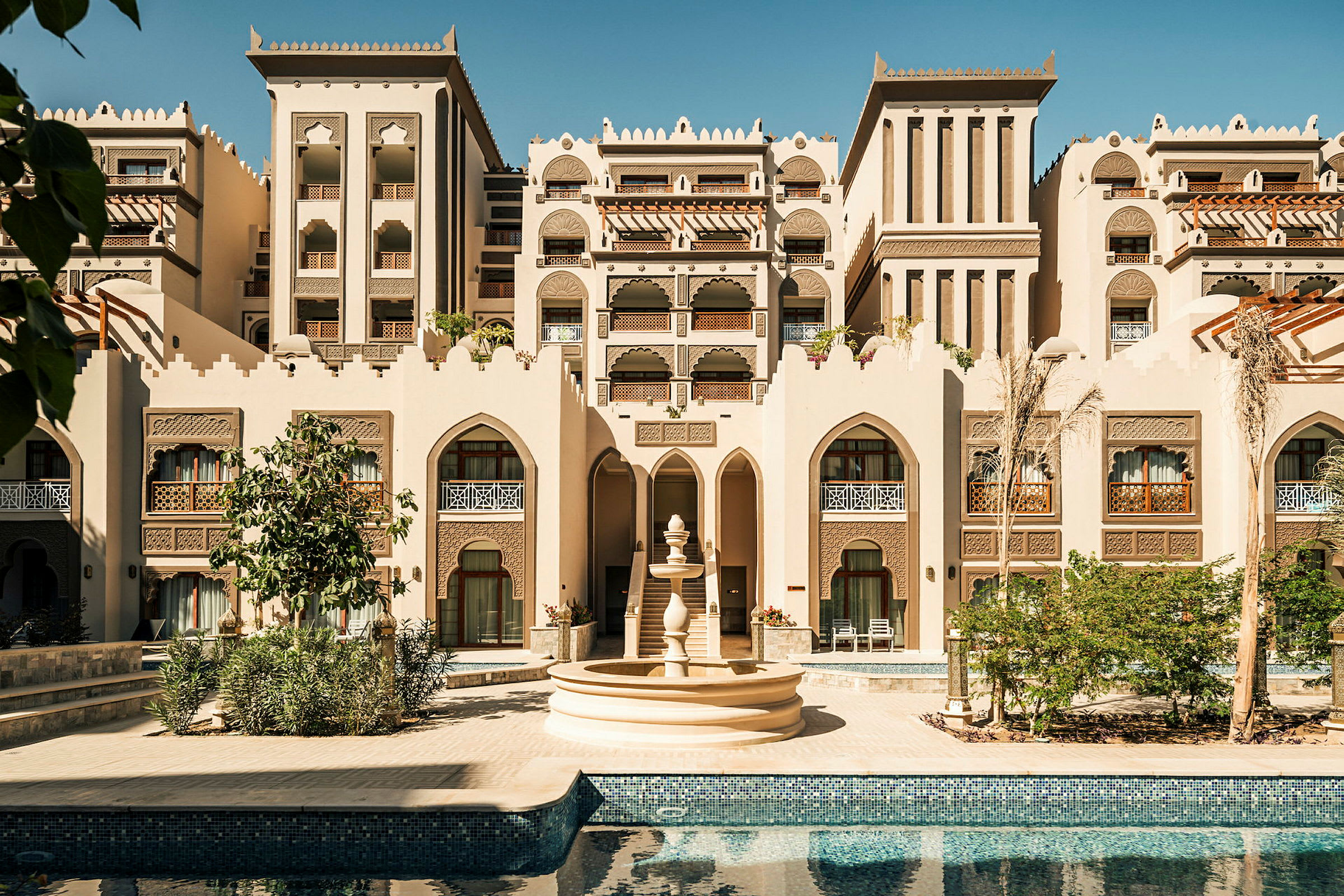 En byggnad i arabisk arkitekturstil med en fontän och en pool i förgrunden. (AI-genererad text)