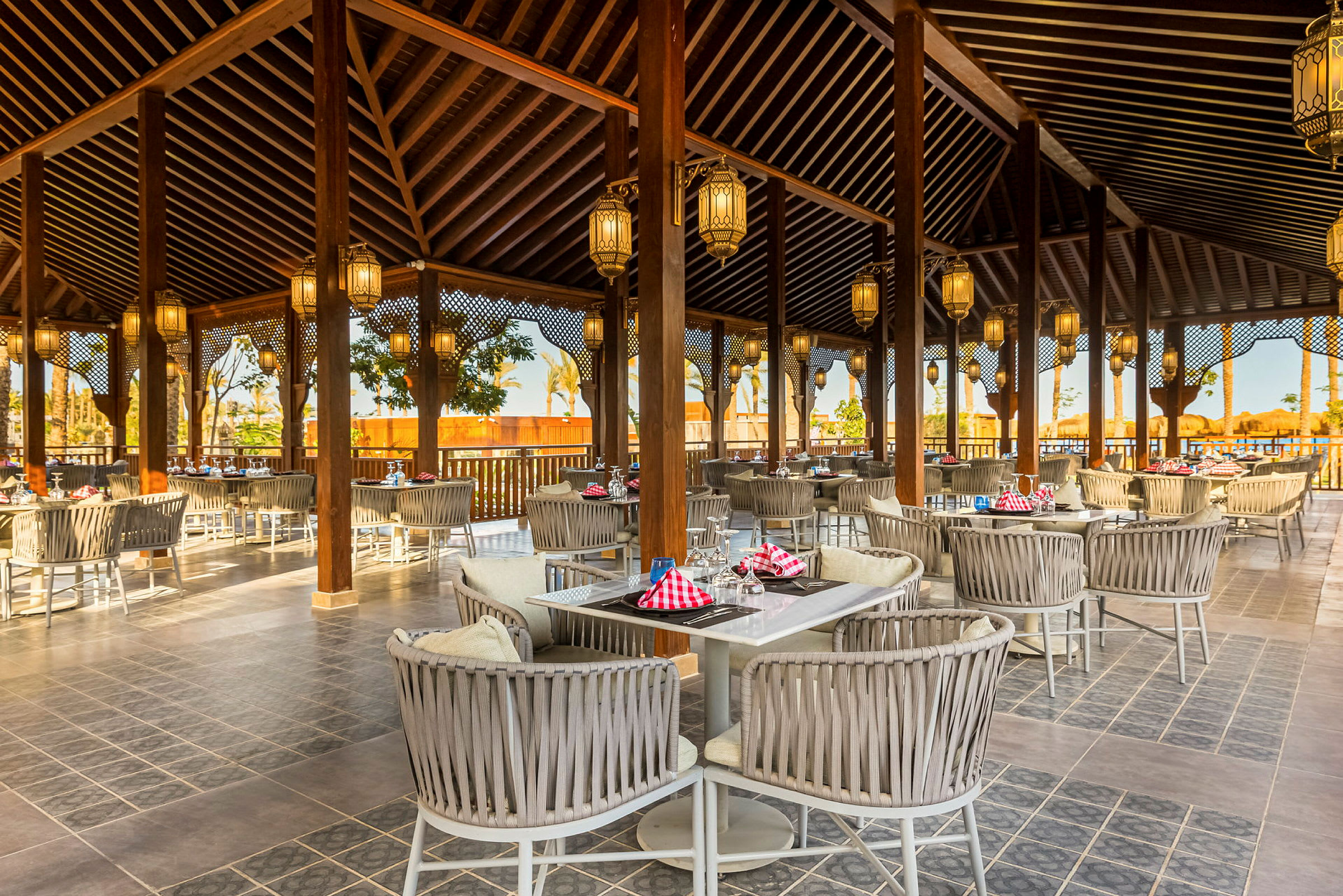 En öppen restaurang med utemöbler och lyktor i taket. (AI-genererad text)