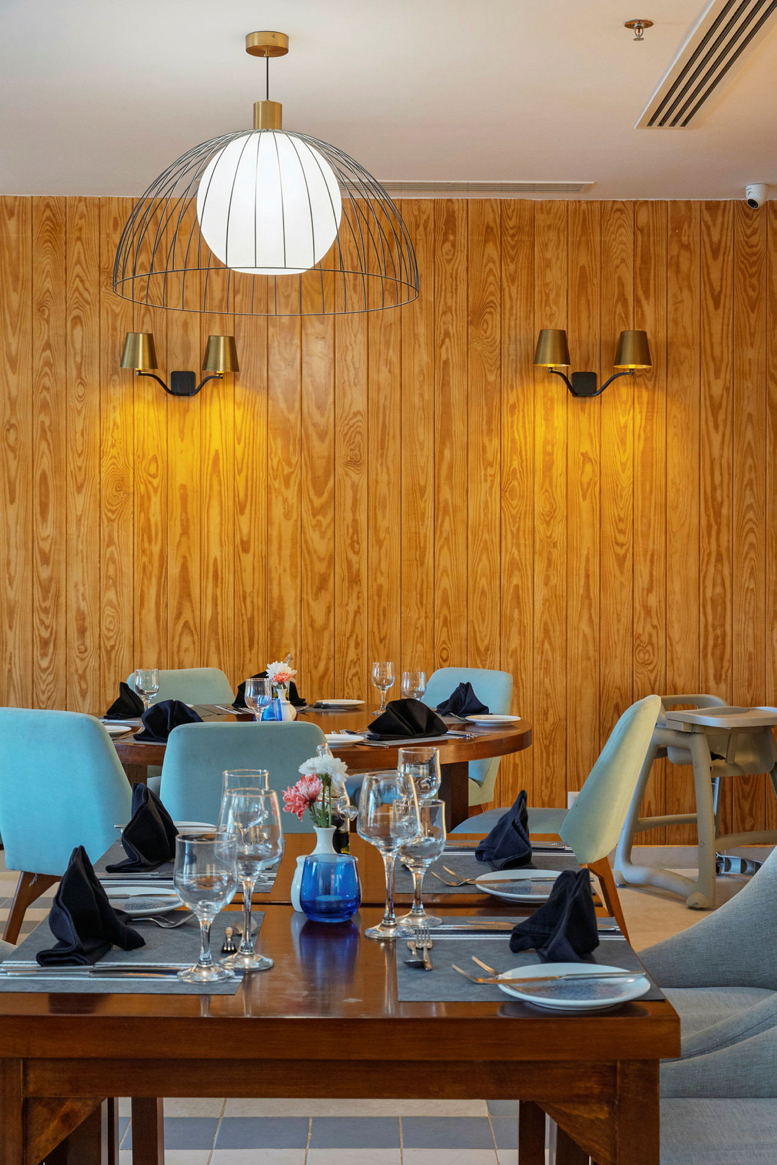 Interiör av en restaurang med träväggar, dukade bord och stolar. (AI-genererad text)