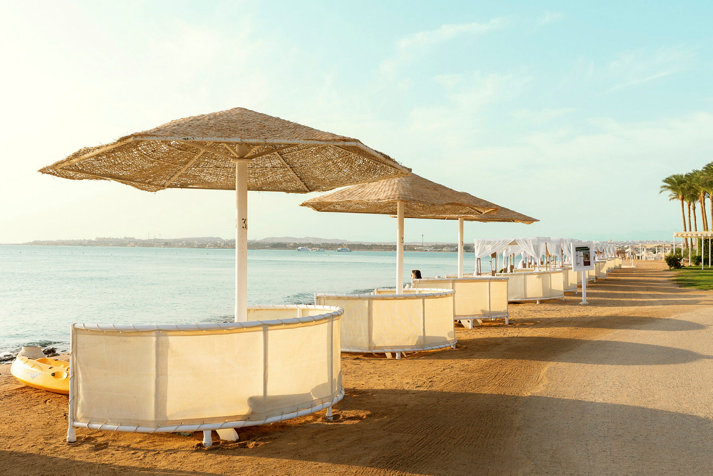 Strand med parasoller och solbarer vid vattnet. (AI-genererad text)