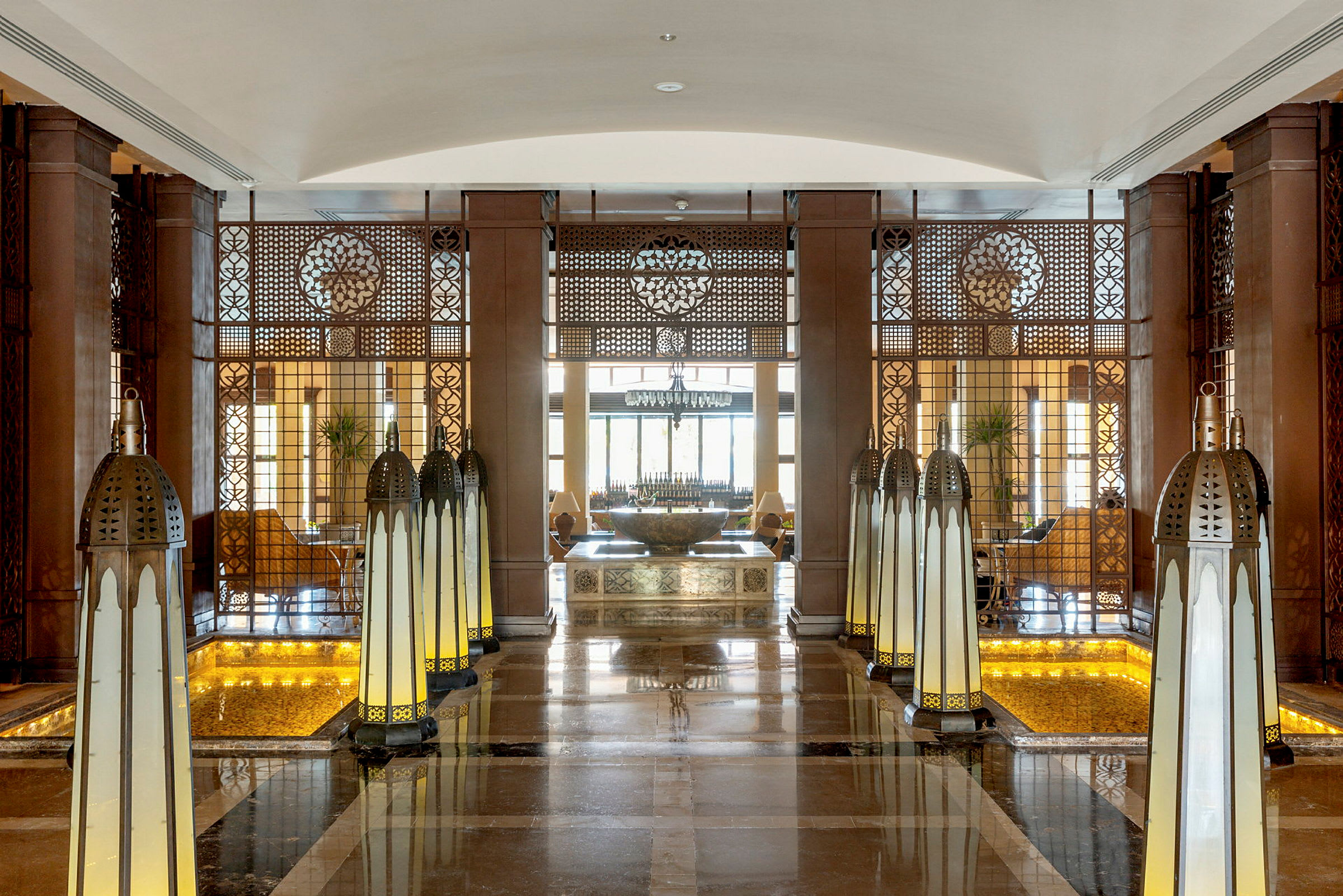 Interiör av en elegant hotelllobby med lampdekorationer och ett centralt bord. (AI-genererad text)