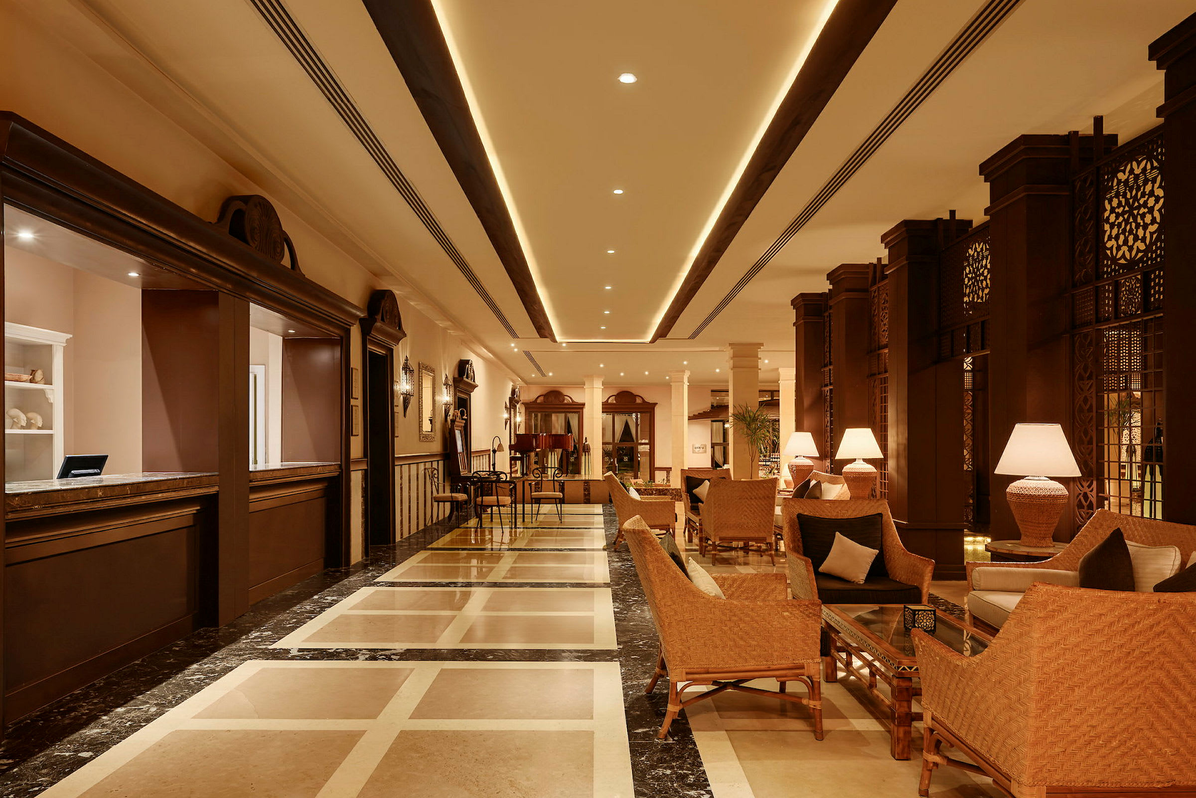 Ett hotellobby med sittplatser, bord och lampor. Receptionen finns till vänster. (AI-genererad text)