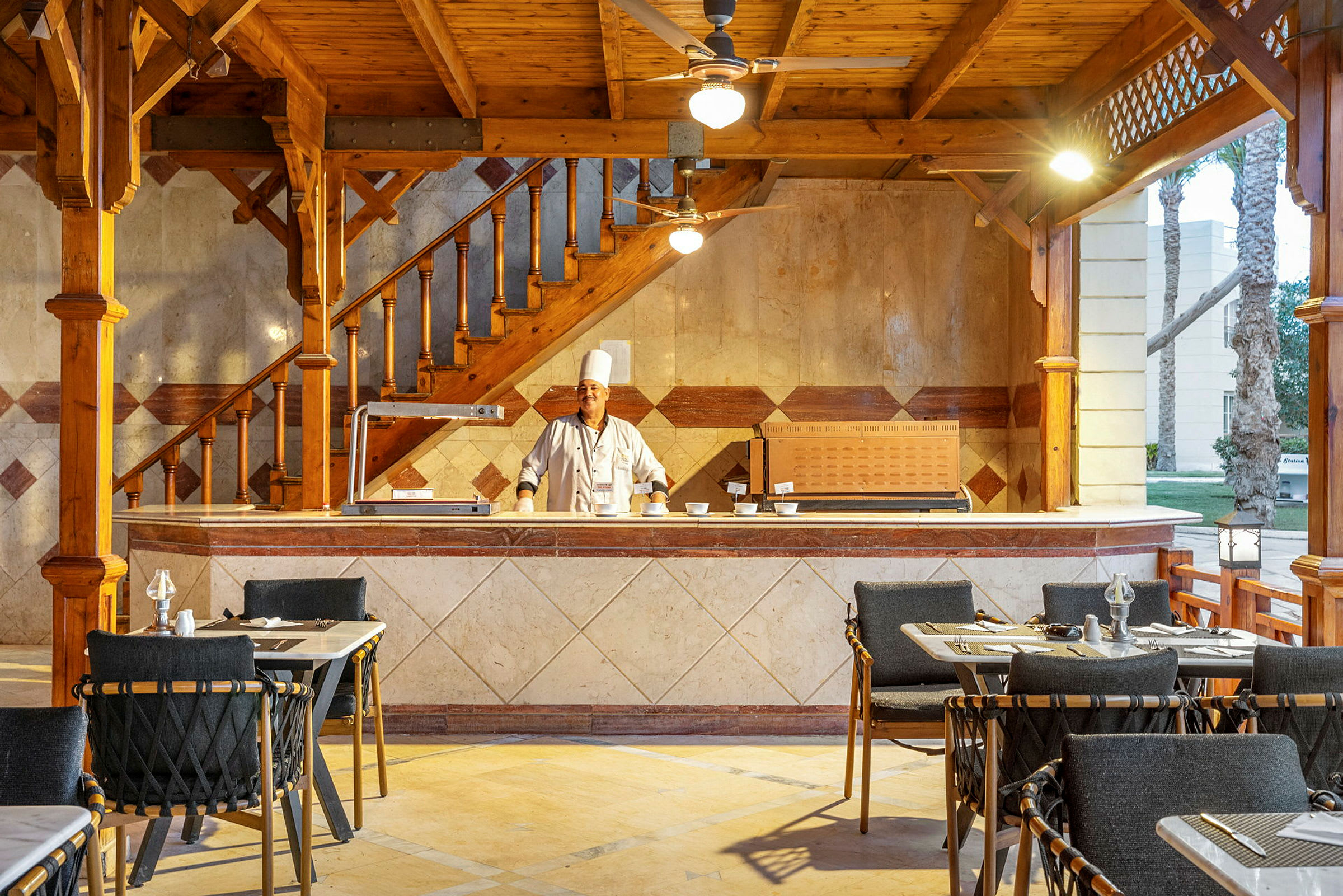 Restaurangområde med synliga bord och stolar samt en serveringsdisk. (AI-genererad text)