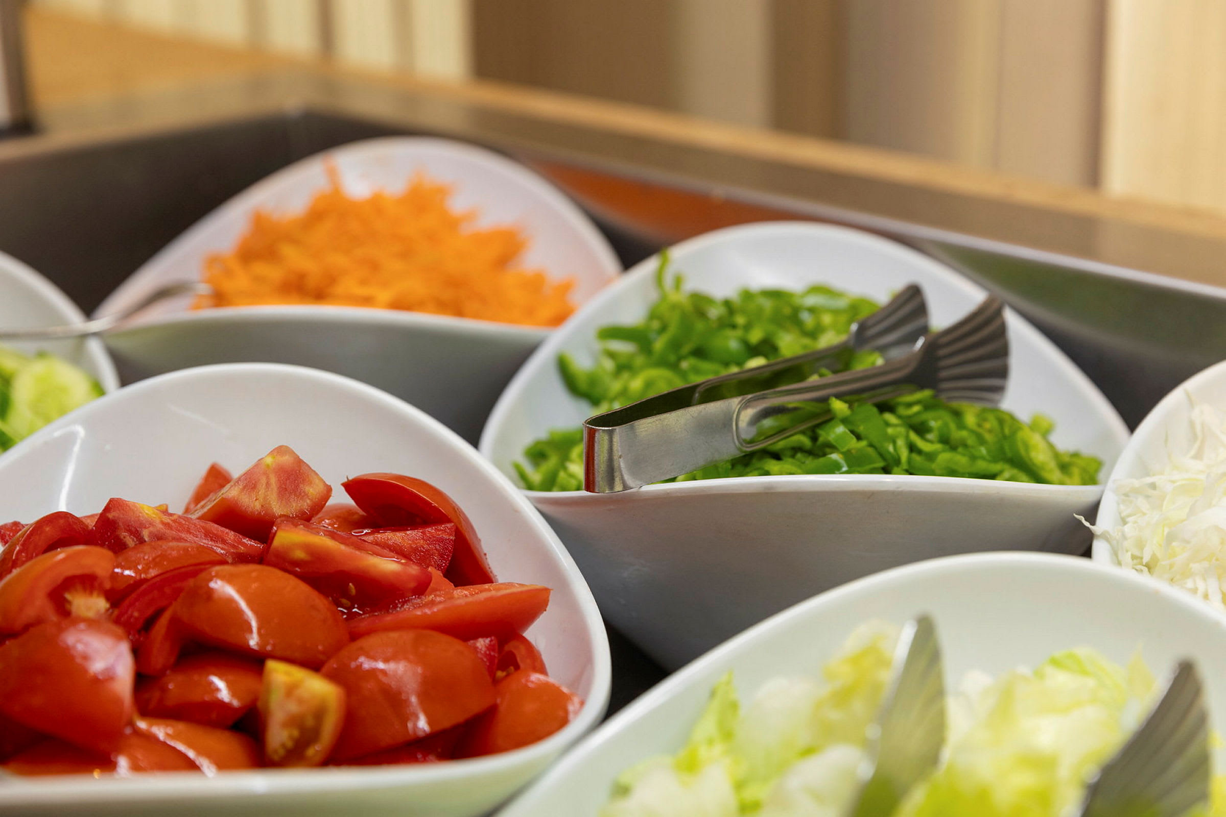 Färska grönsaker uppställda i skålar, inklusive tomater, morötter och paprika. (AI-genererad text)