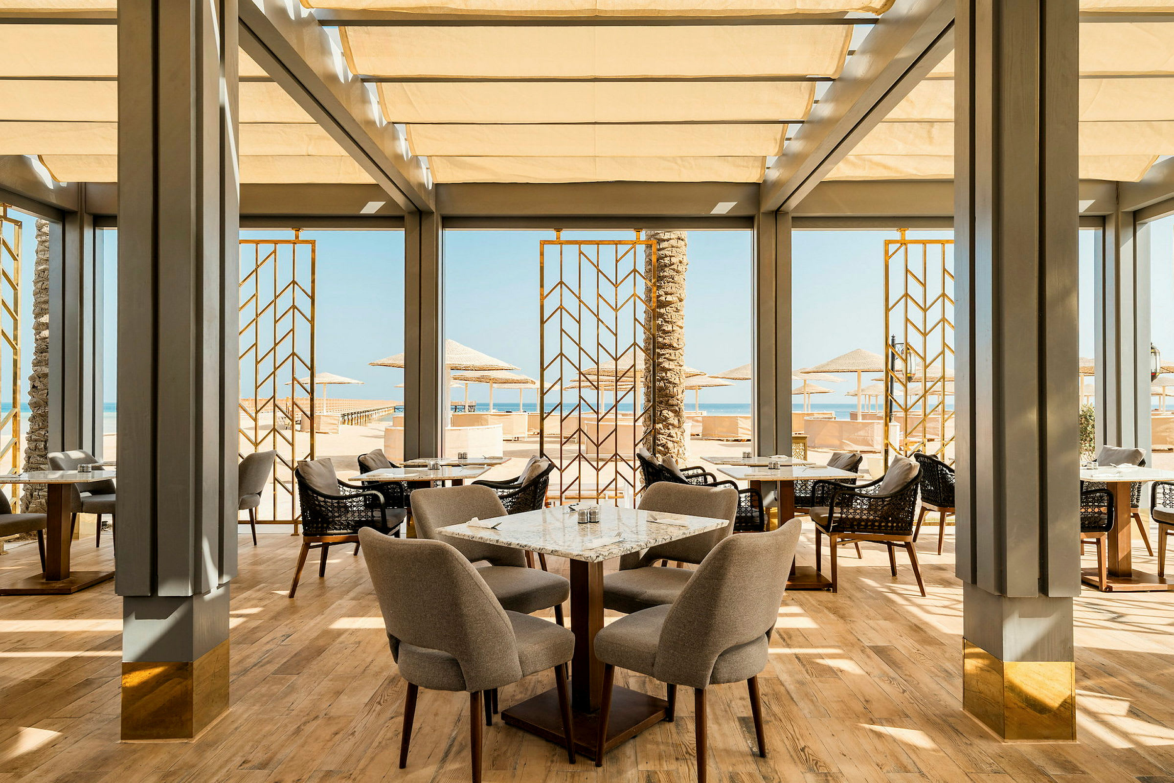 En elegant restaurang med stora fönster som vetter mot stranden och havsutsikten (AI-genererad text)